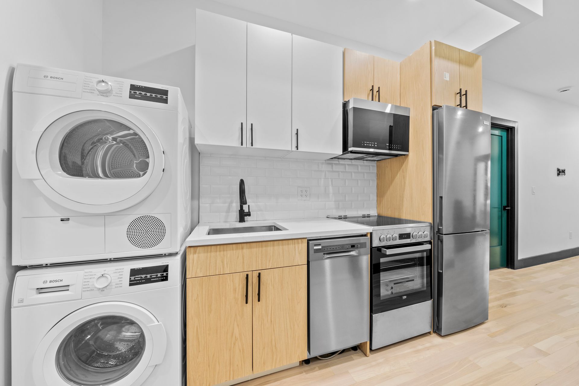A kitchen with a washer and dryer stacked on top of each other.