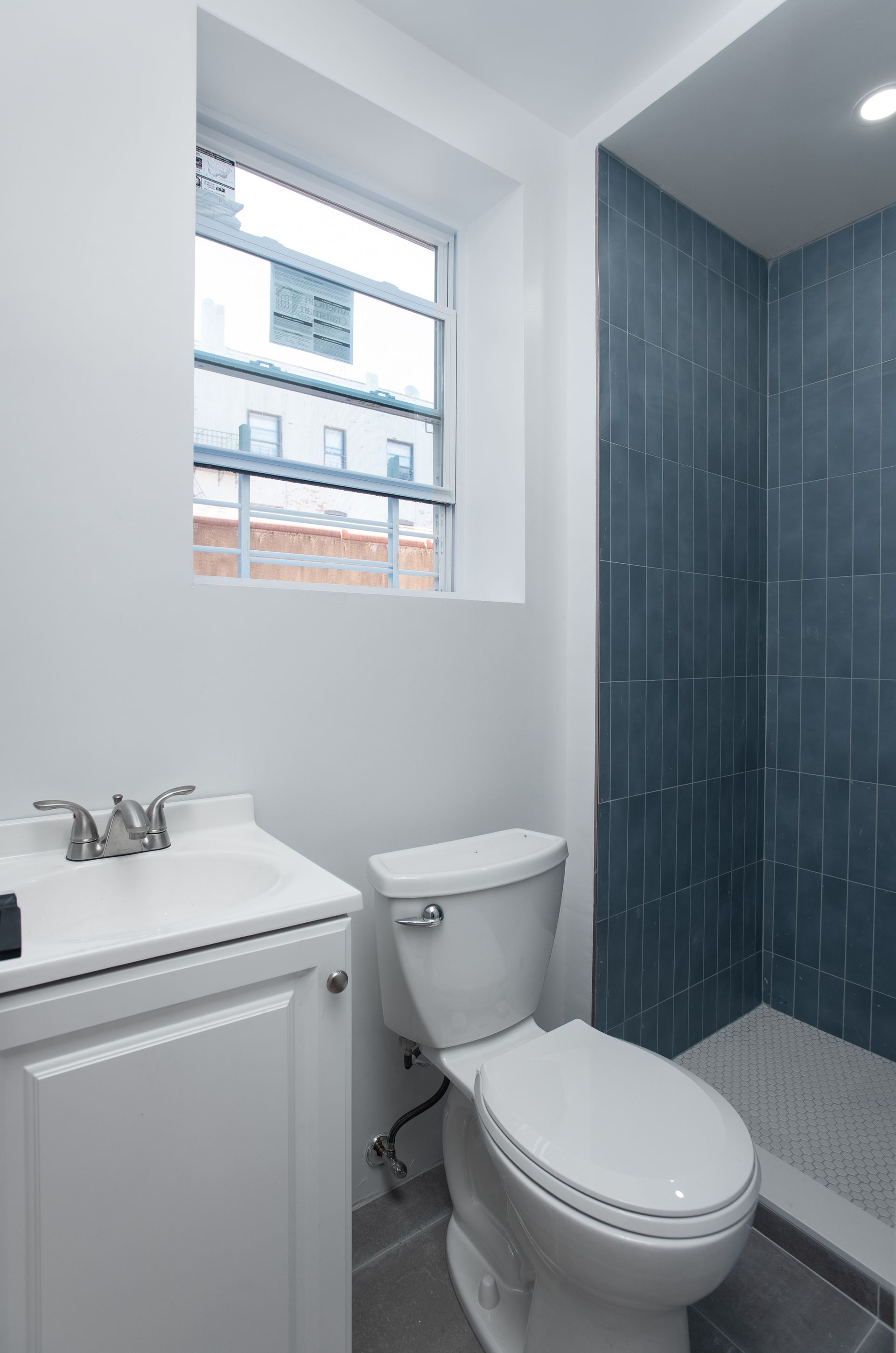 A bathroom with a toilet , sink and window