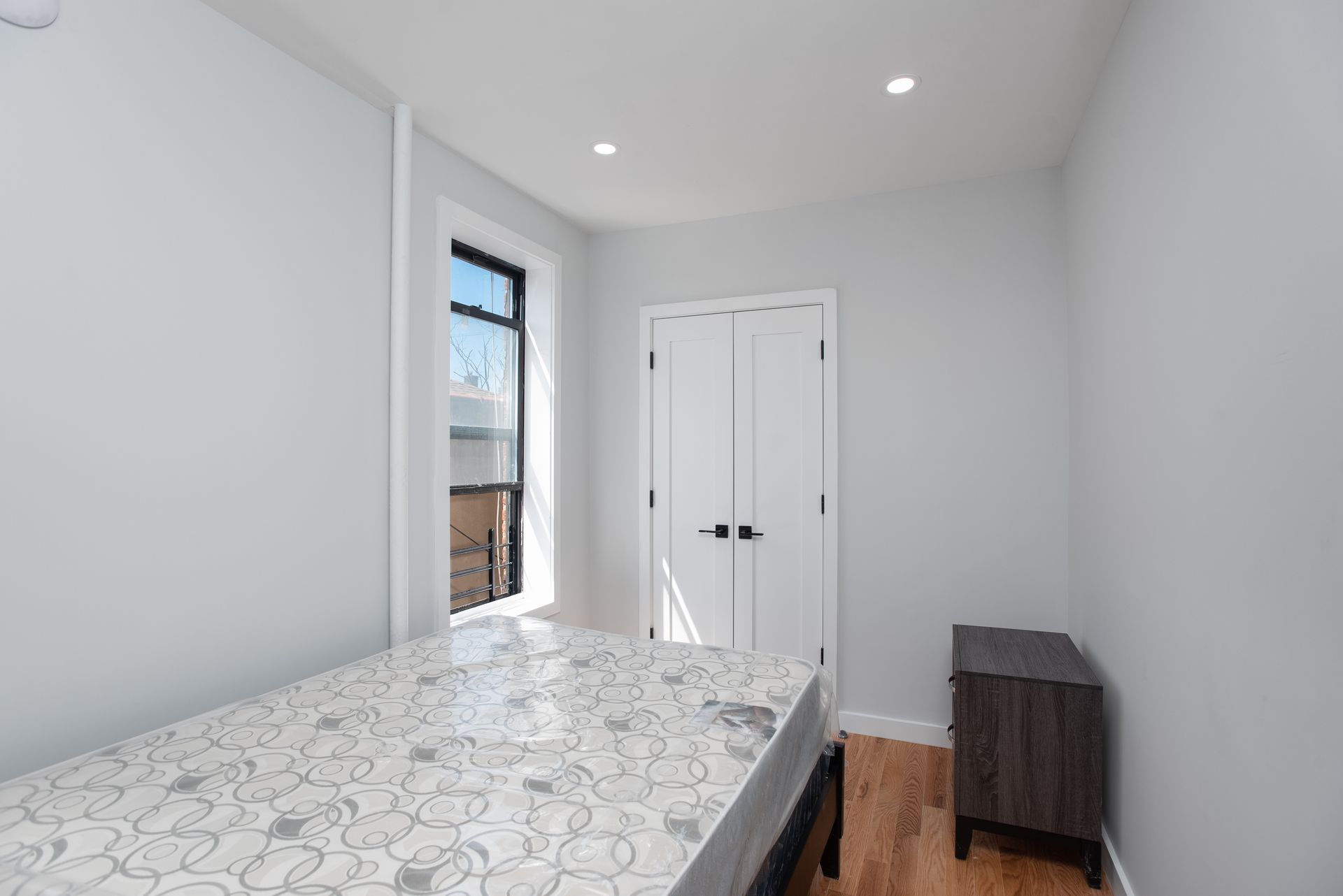 A bedroom with a bed , nightstand , and window.