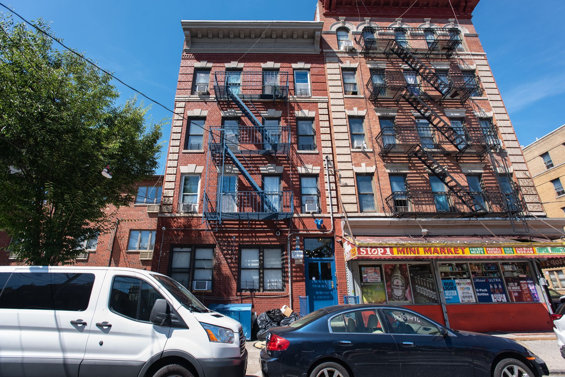 A white van and a black car are parked in front of a brick building