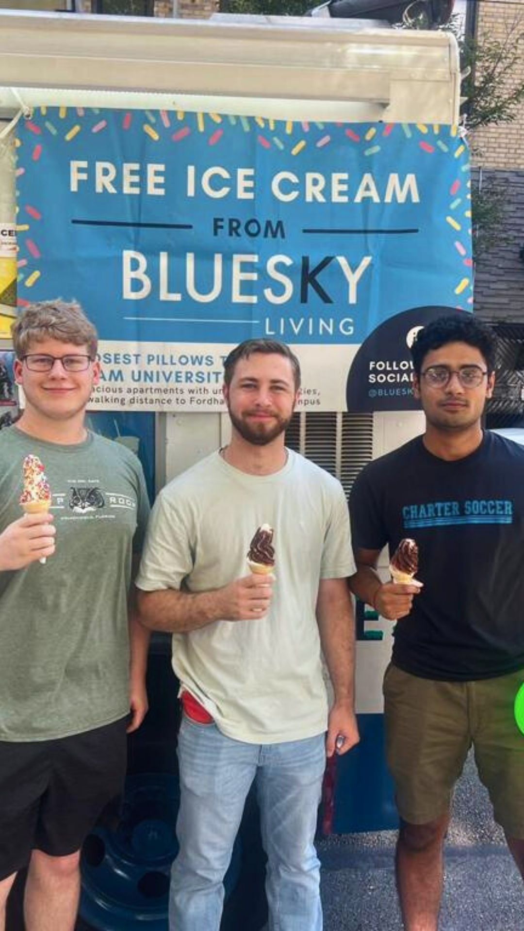 Three men are standing in front of a blue sky ice cream truck holding ice cream cones.