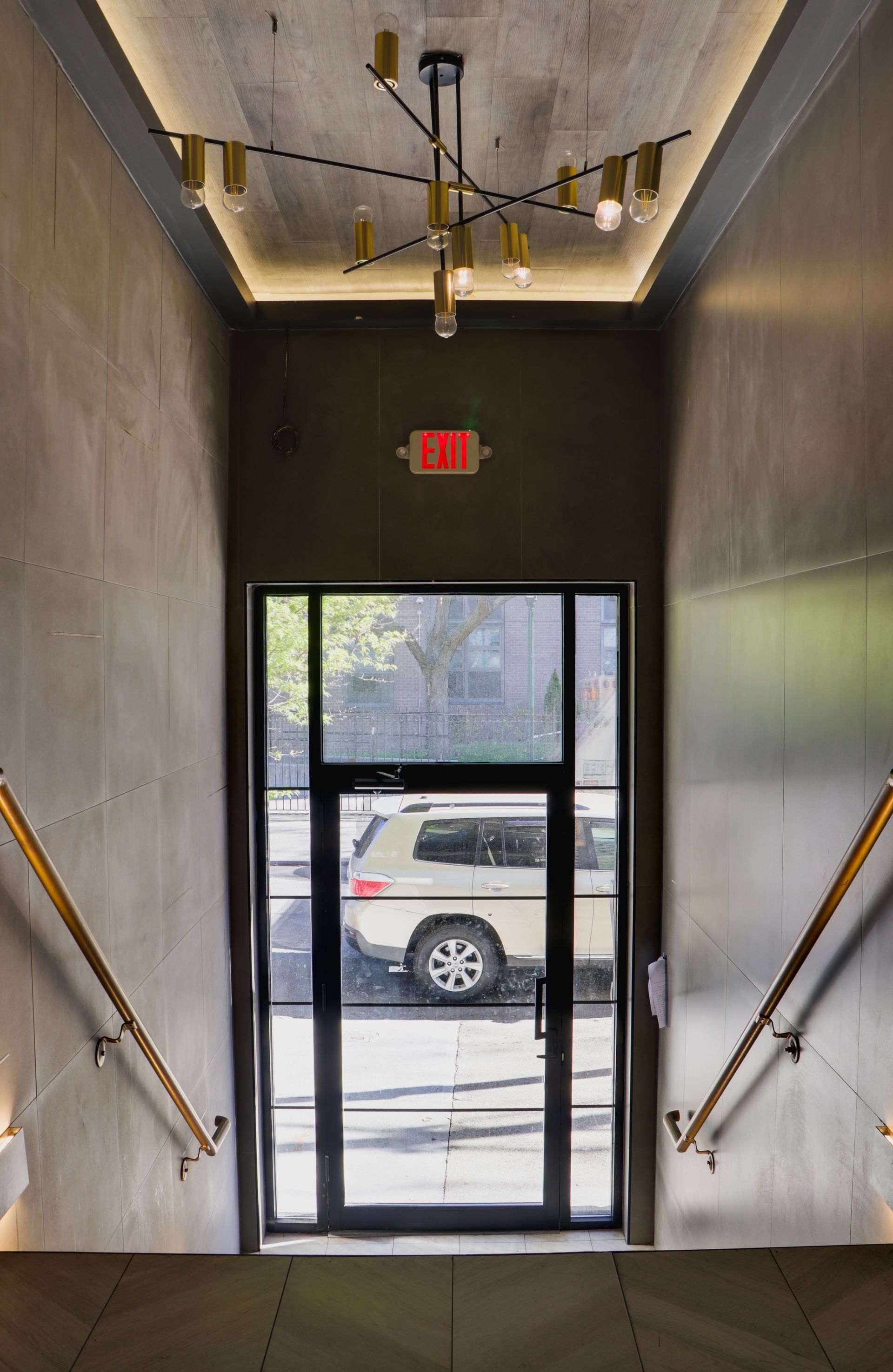 A staircase leading up to a door with a red exit sign above it