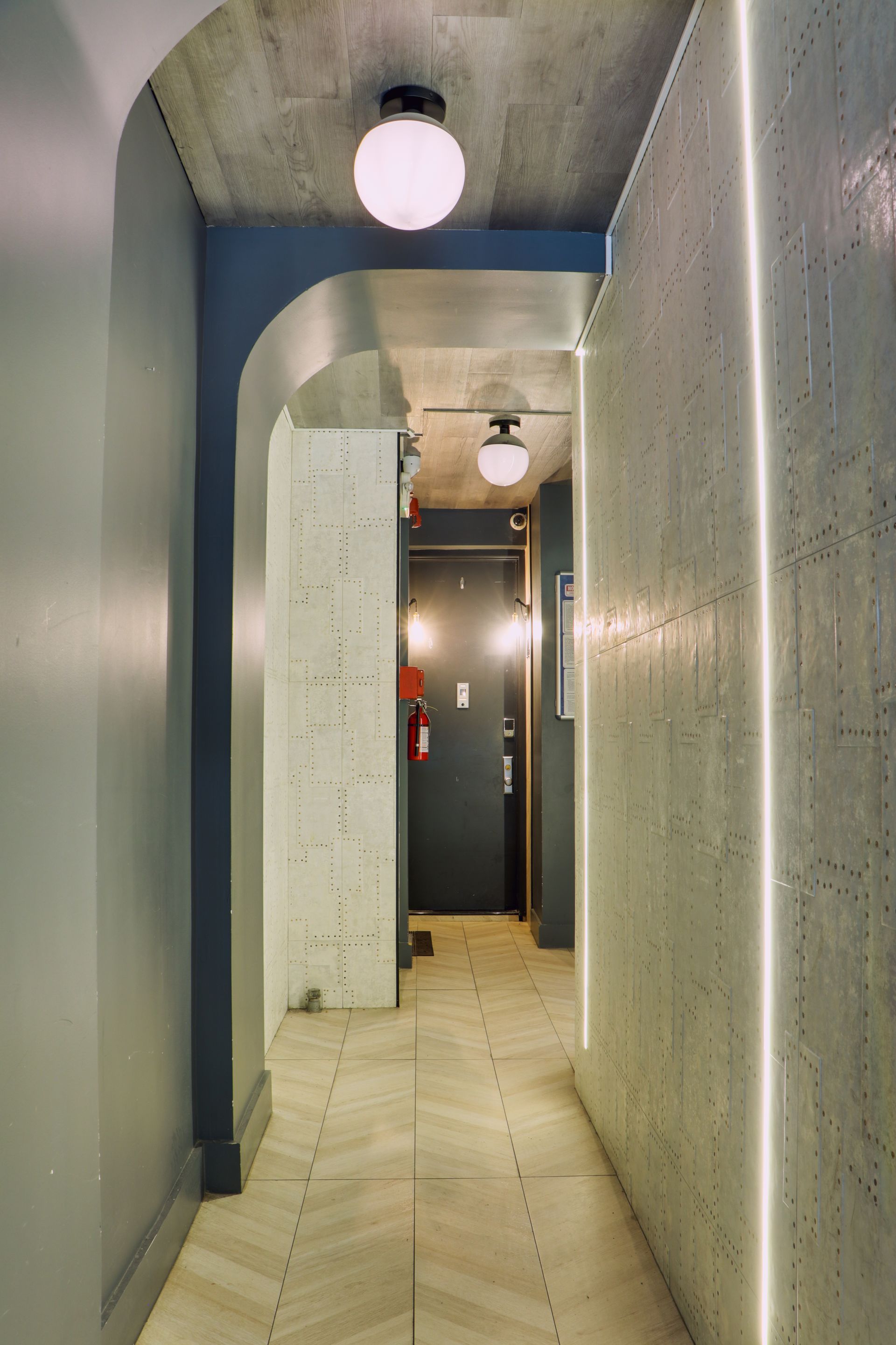 A long hallway with a door and a light on the wall