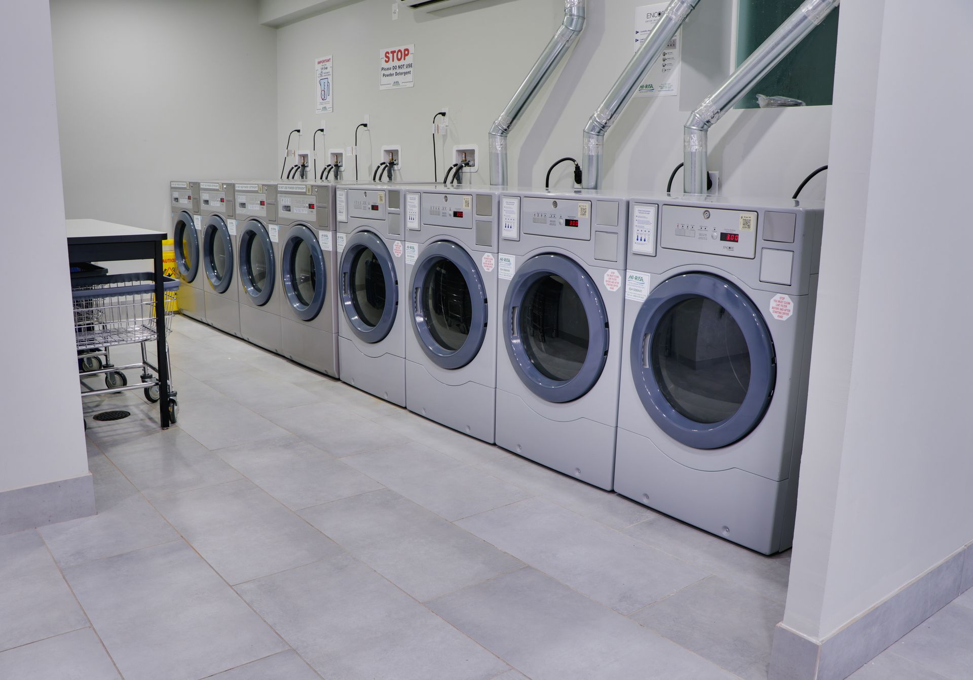 A row of washing machines are lined up in a laundromat.