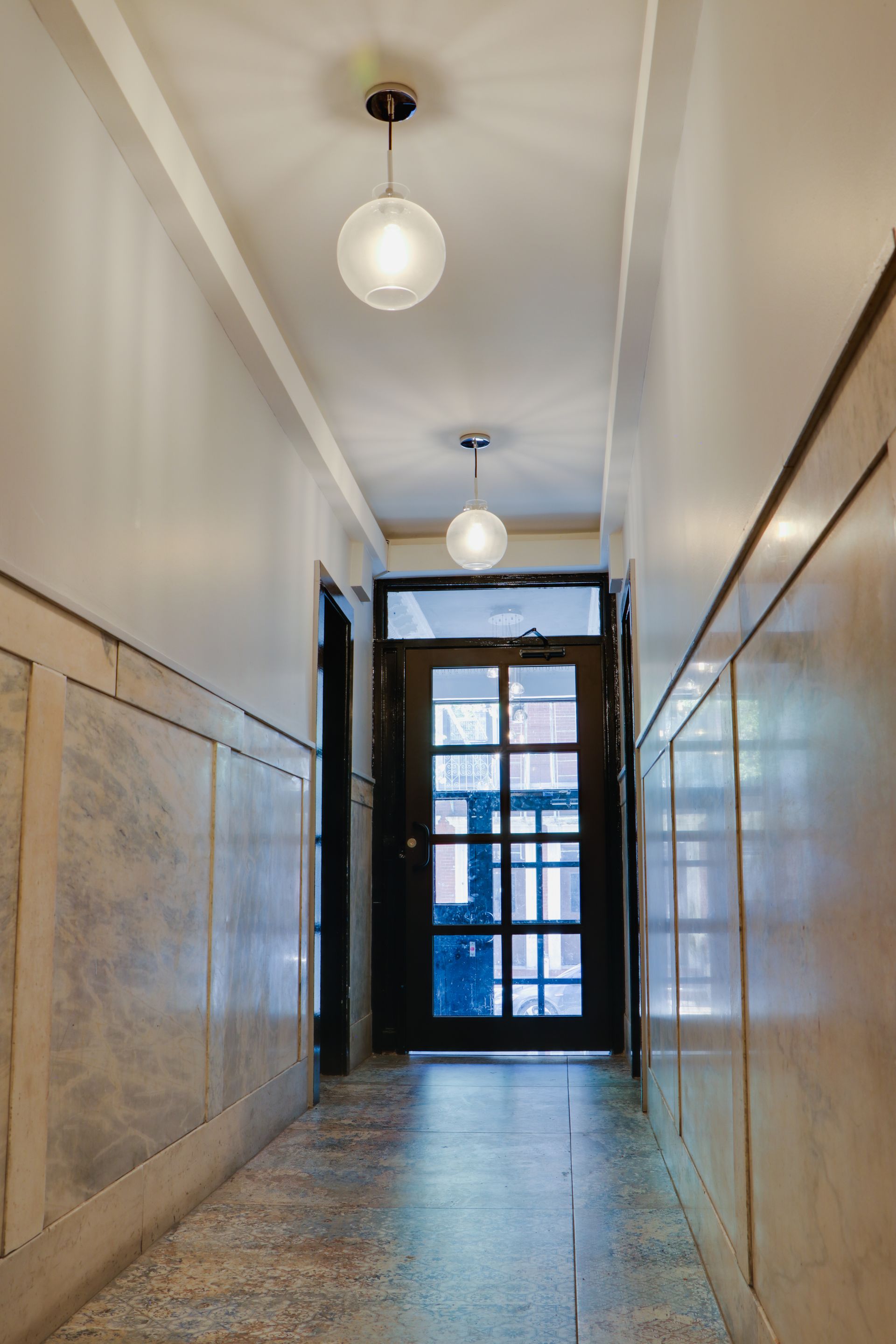 A hallway with a door and two lights on the ceiling