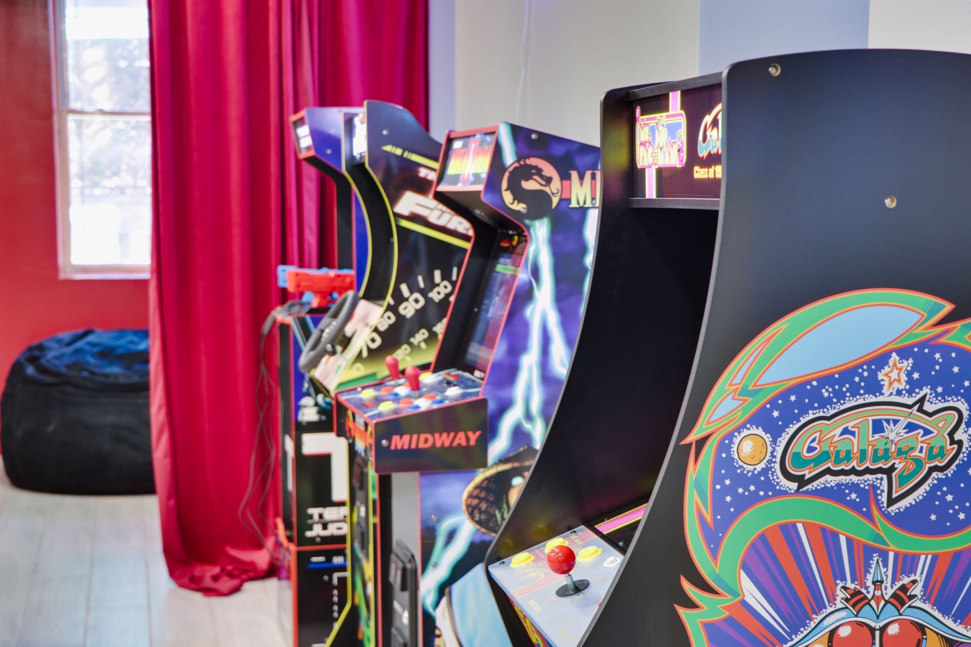 A bunch of arcade games are lined up in a room.