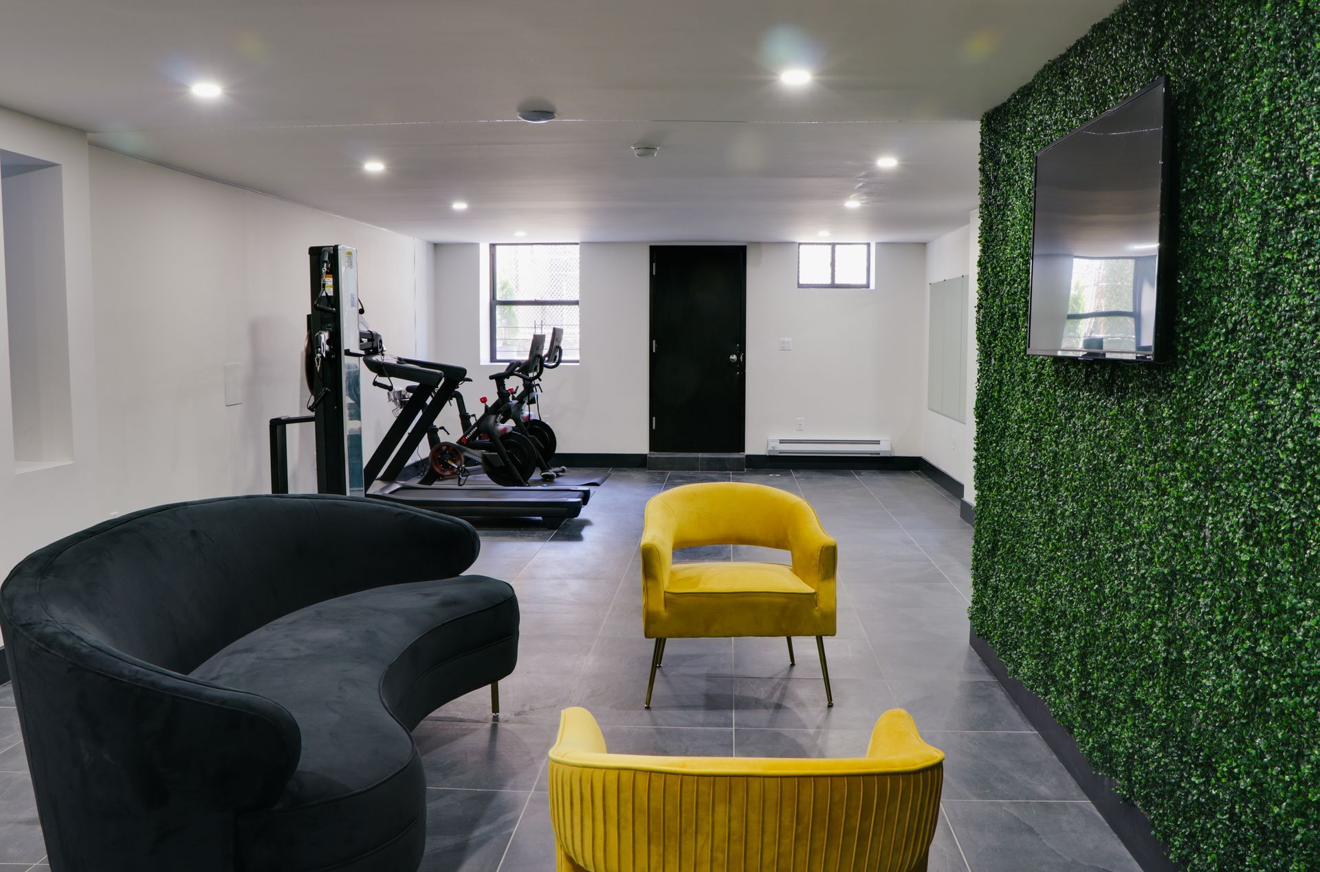A living room with a couch , chairs and a treadmill.