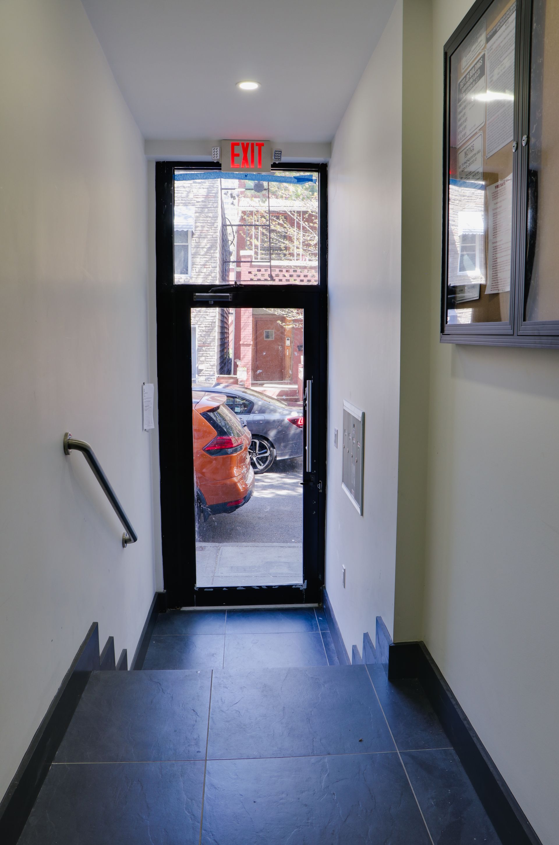A hallway with a red exit sign above the door