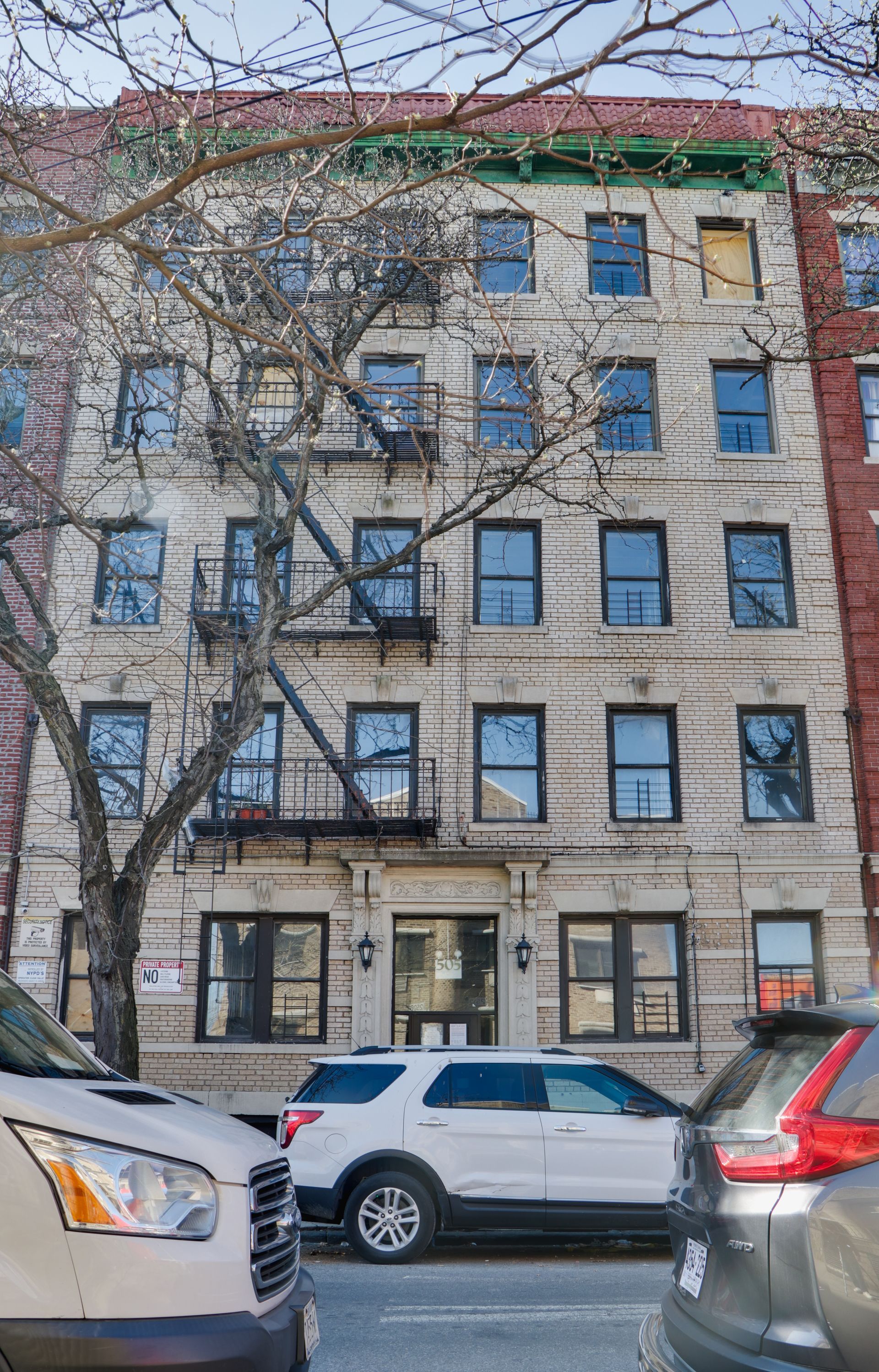 A white suv is parked in front of a large building.