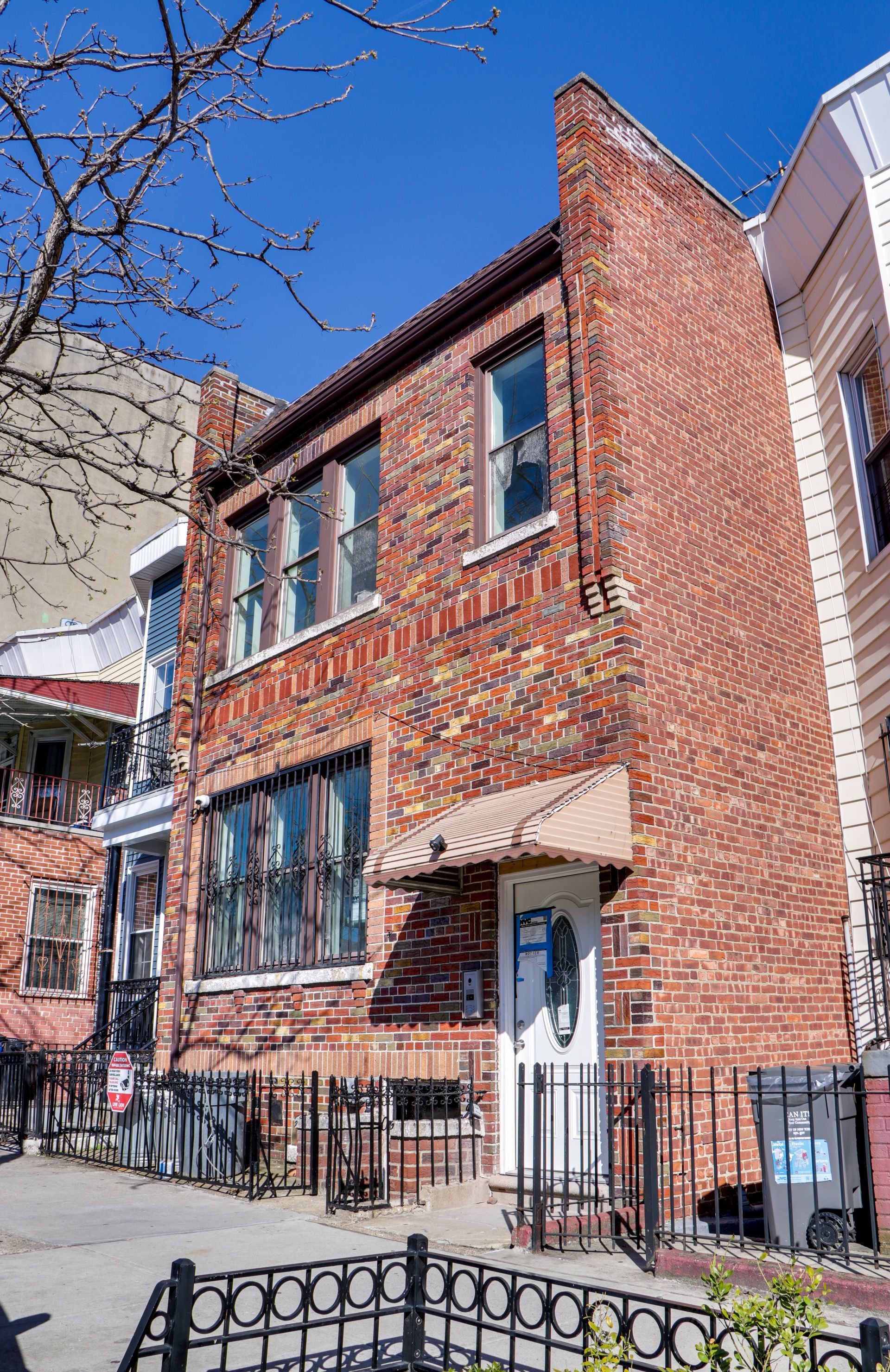 A brick building with a white door and a fence in front of it.