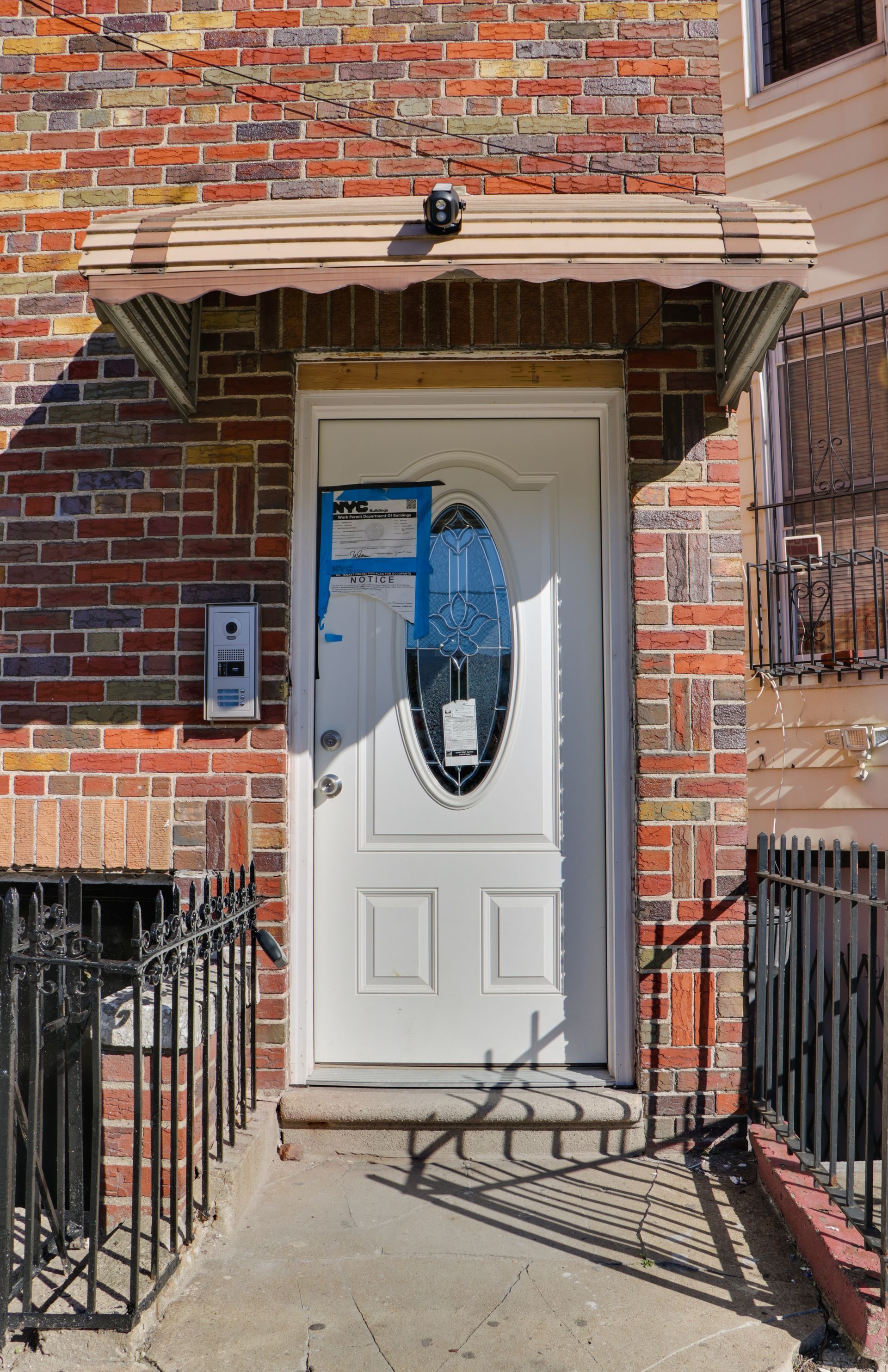 A white door is on a brick building with a canopy over it.