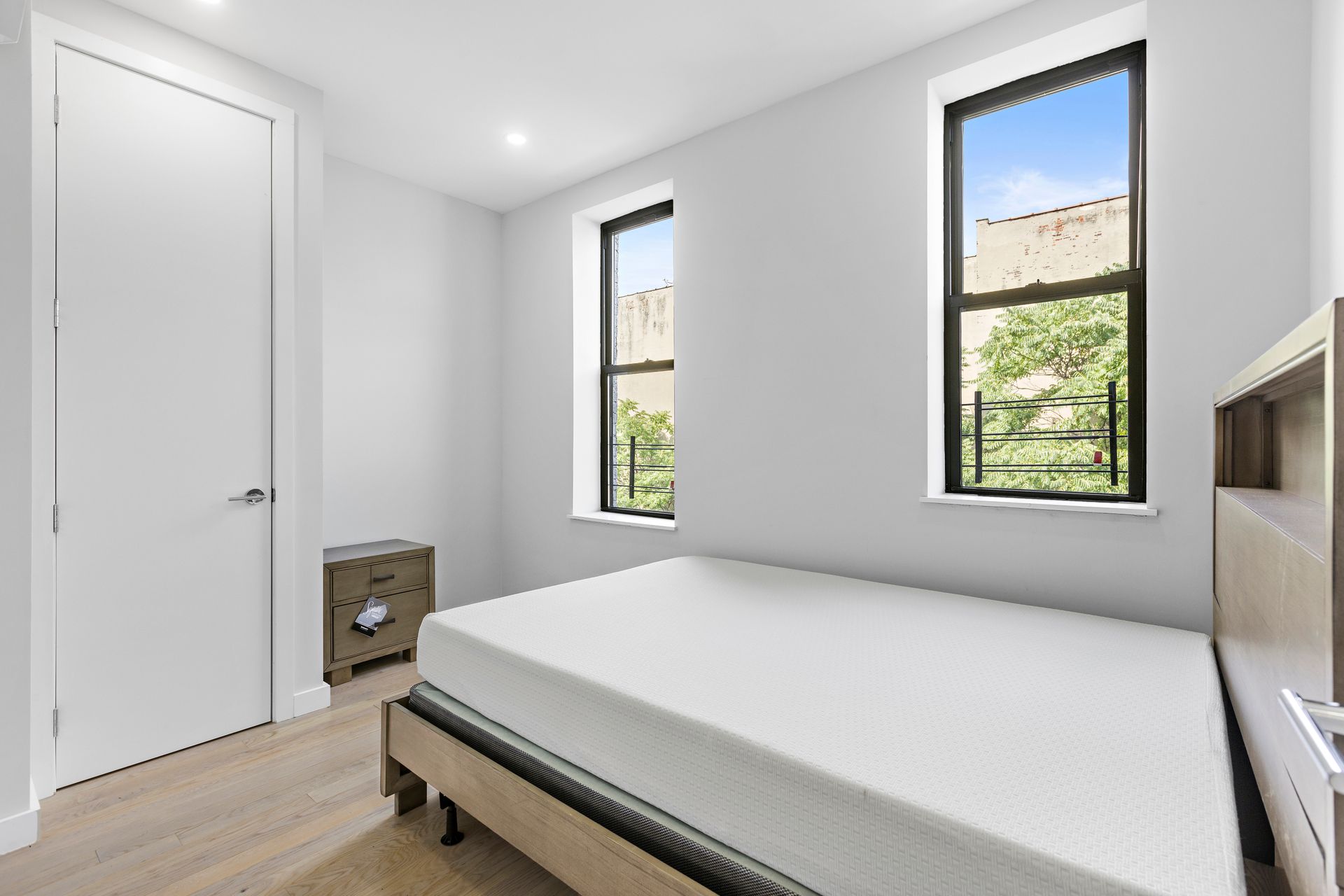 A bedroom with a mattress and two windows