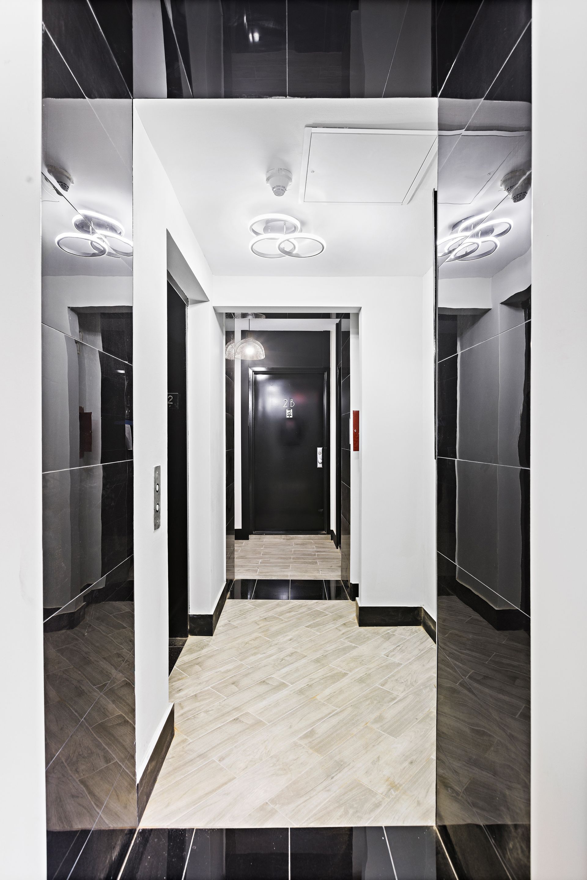 A hallway with black and white tiles and a mirrored ceiling.