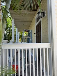 A porch with a white railing and a ladder on it.