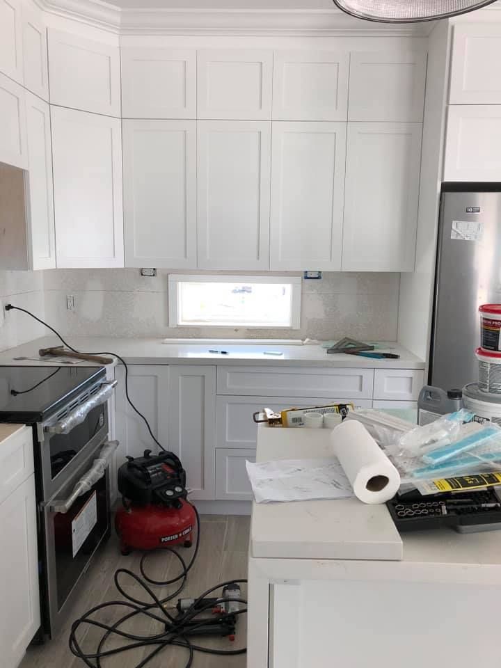 A kitchen with white cabinets and a compressor on the floor.
