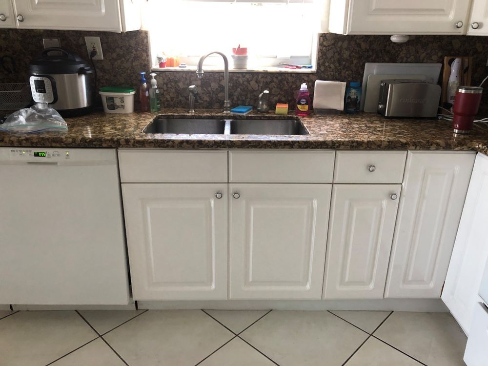 A kitchen with white cabinets and a stainless steel sink