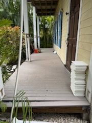 A wooden porch with a stack of white boxes on the side of a house.
