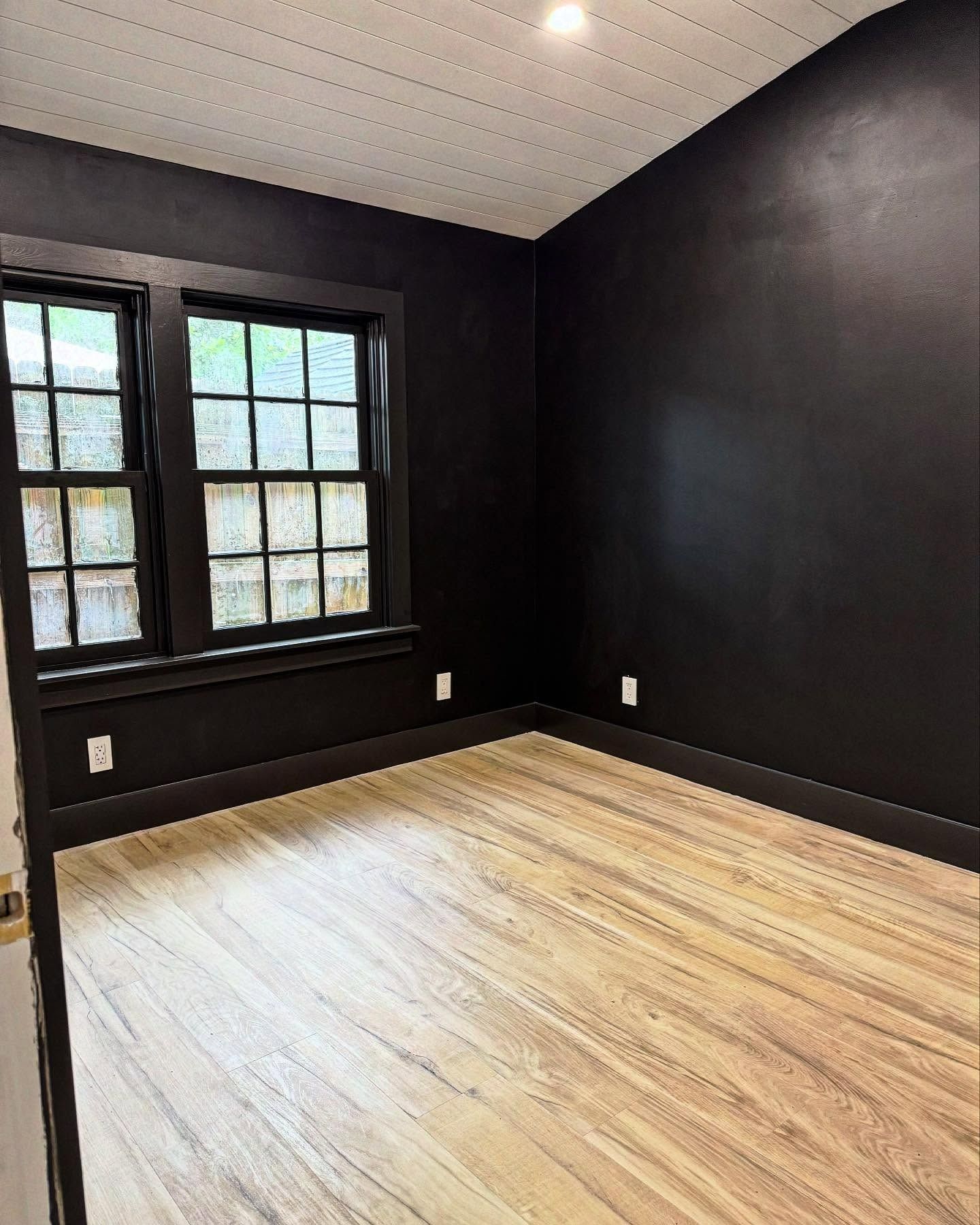 An empty room with black walls and wooden floors.