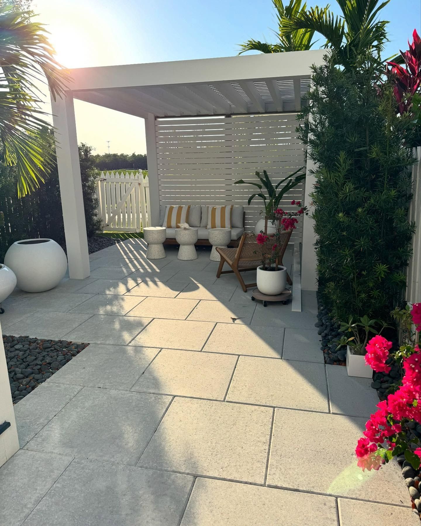 A patio with a pergola , chairs and potted plants