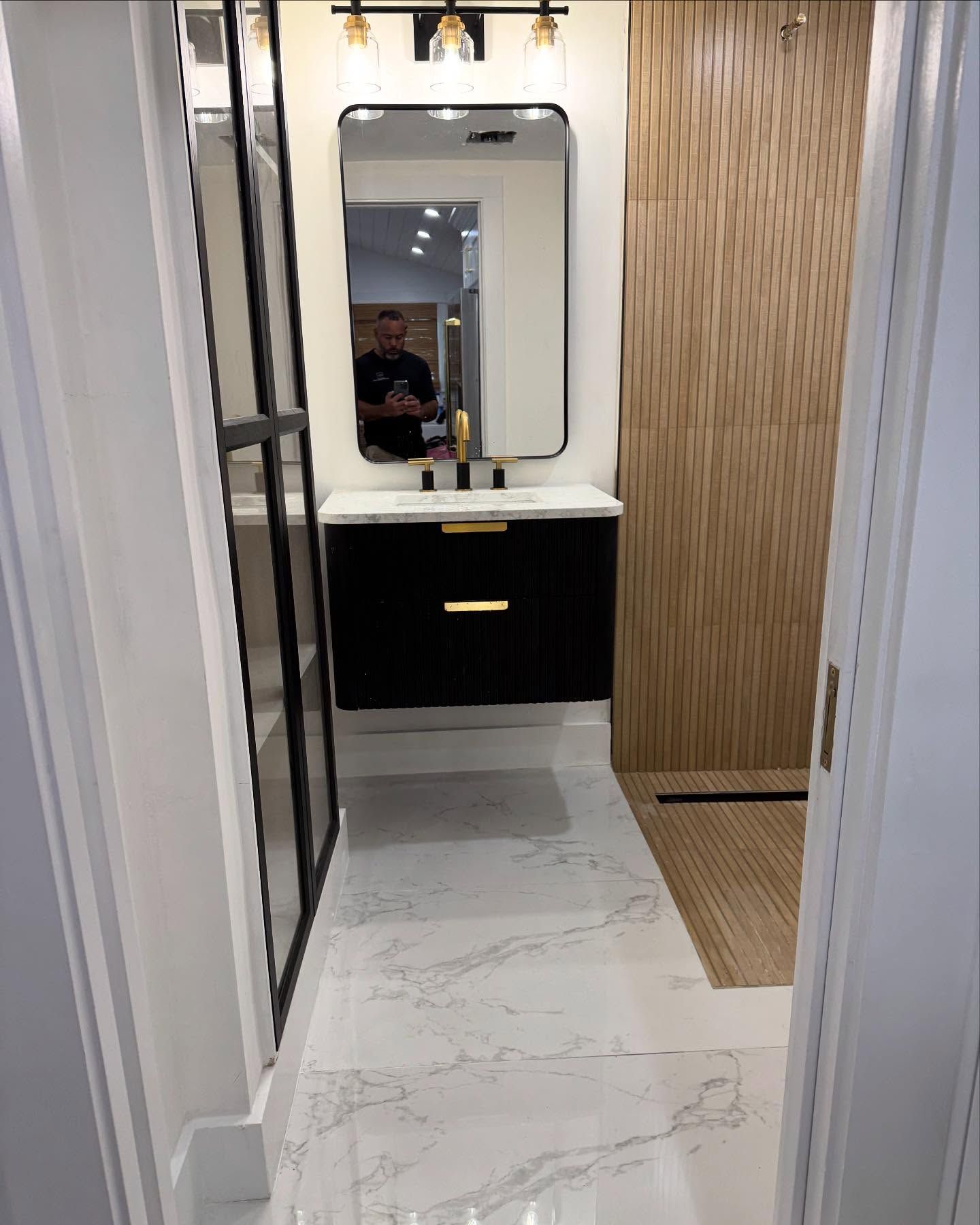 A bathroom with a sink , mirror and walk in shower.