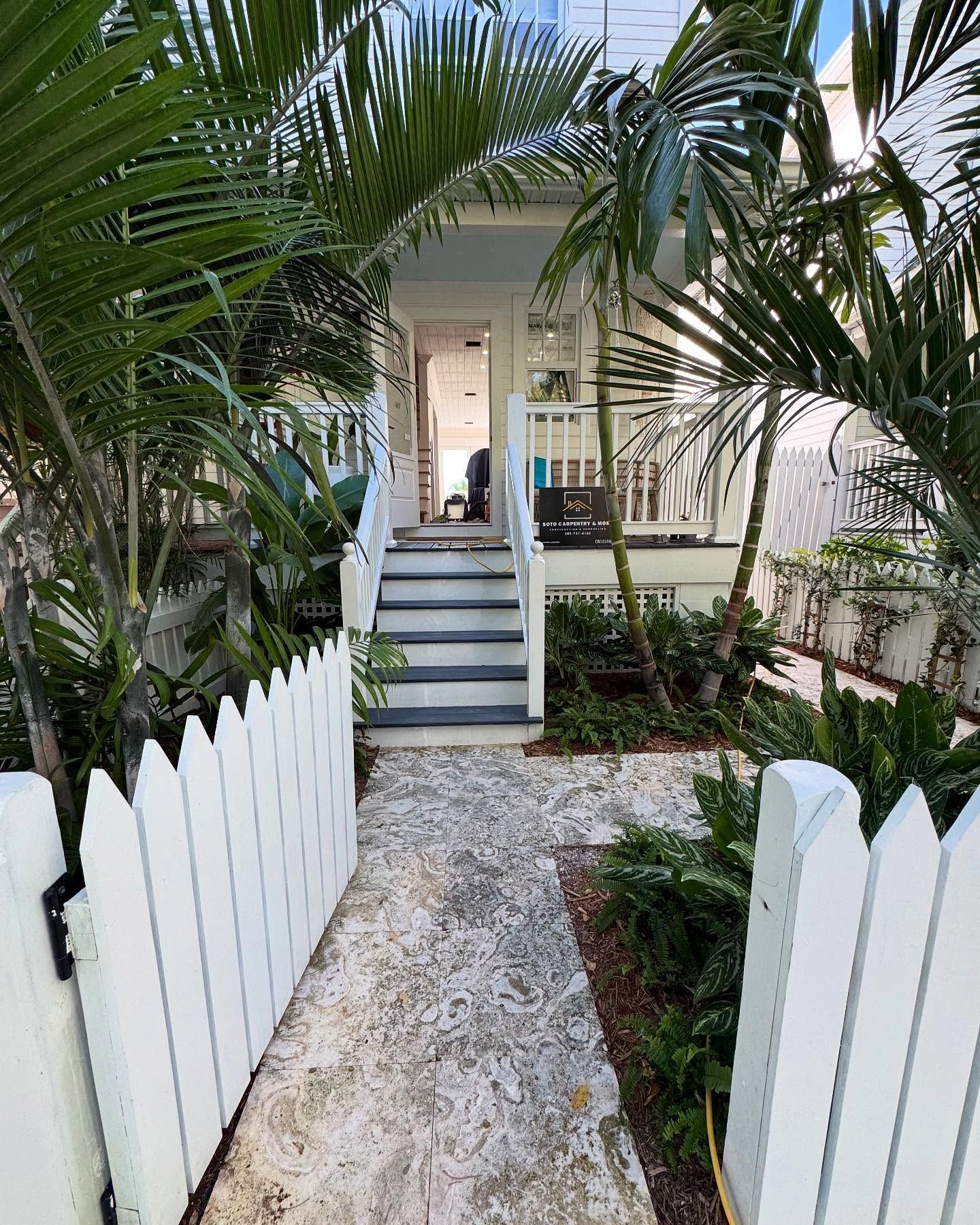 A white picket fence surrounds a path leading to a house.