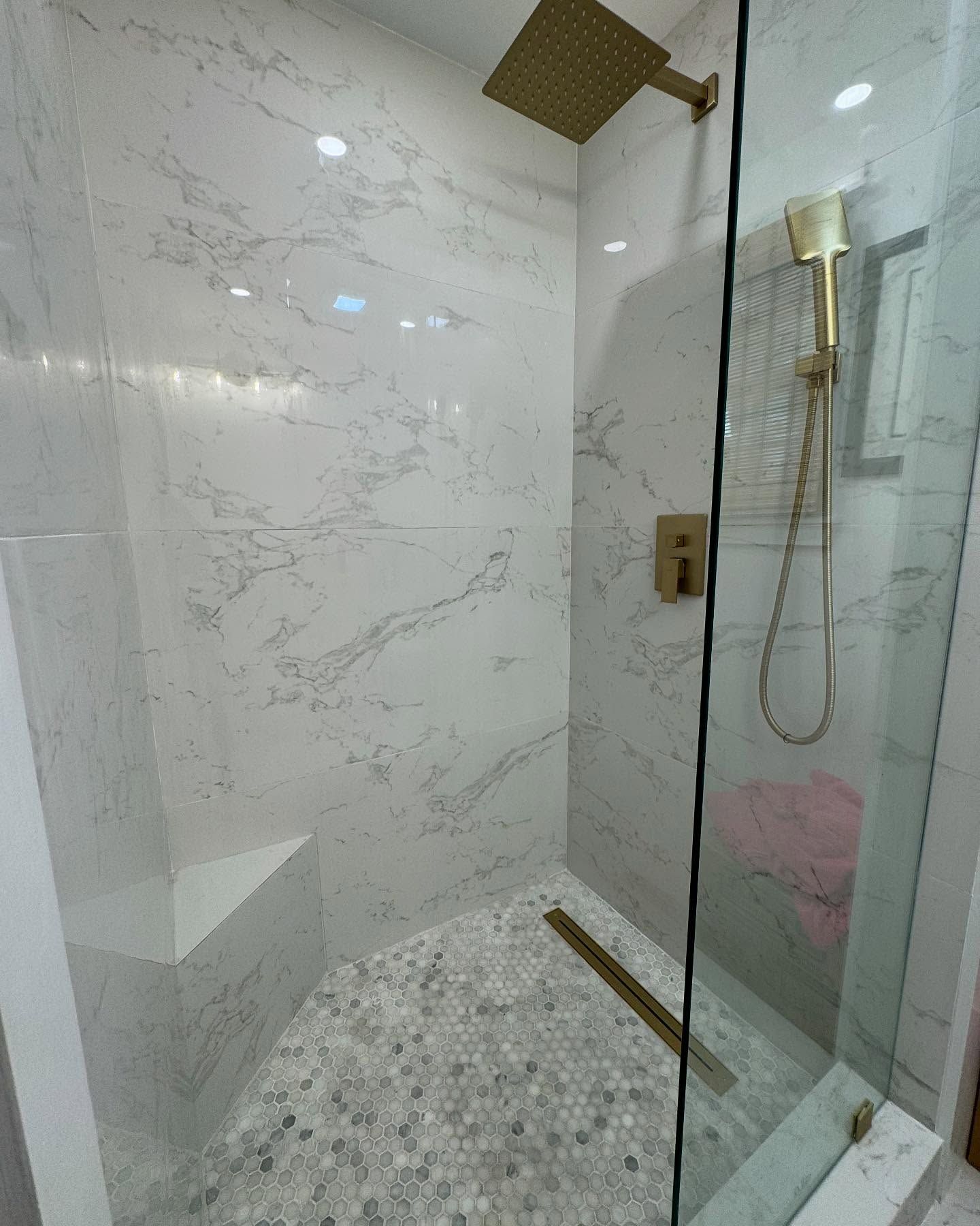 A bathroom with a walk in shower and a gold shower head.