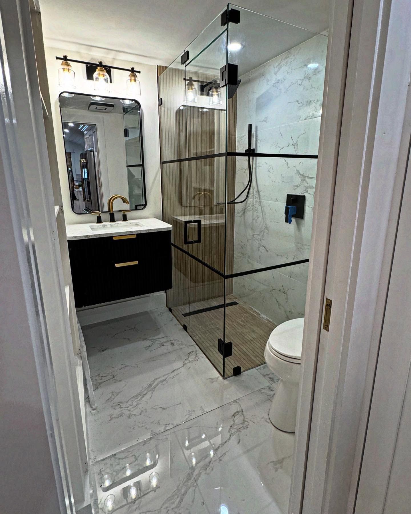 A bathroom with a toilet , sink , shower and mirror.
