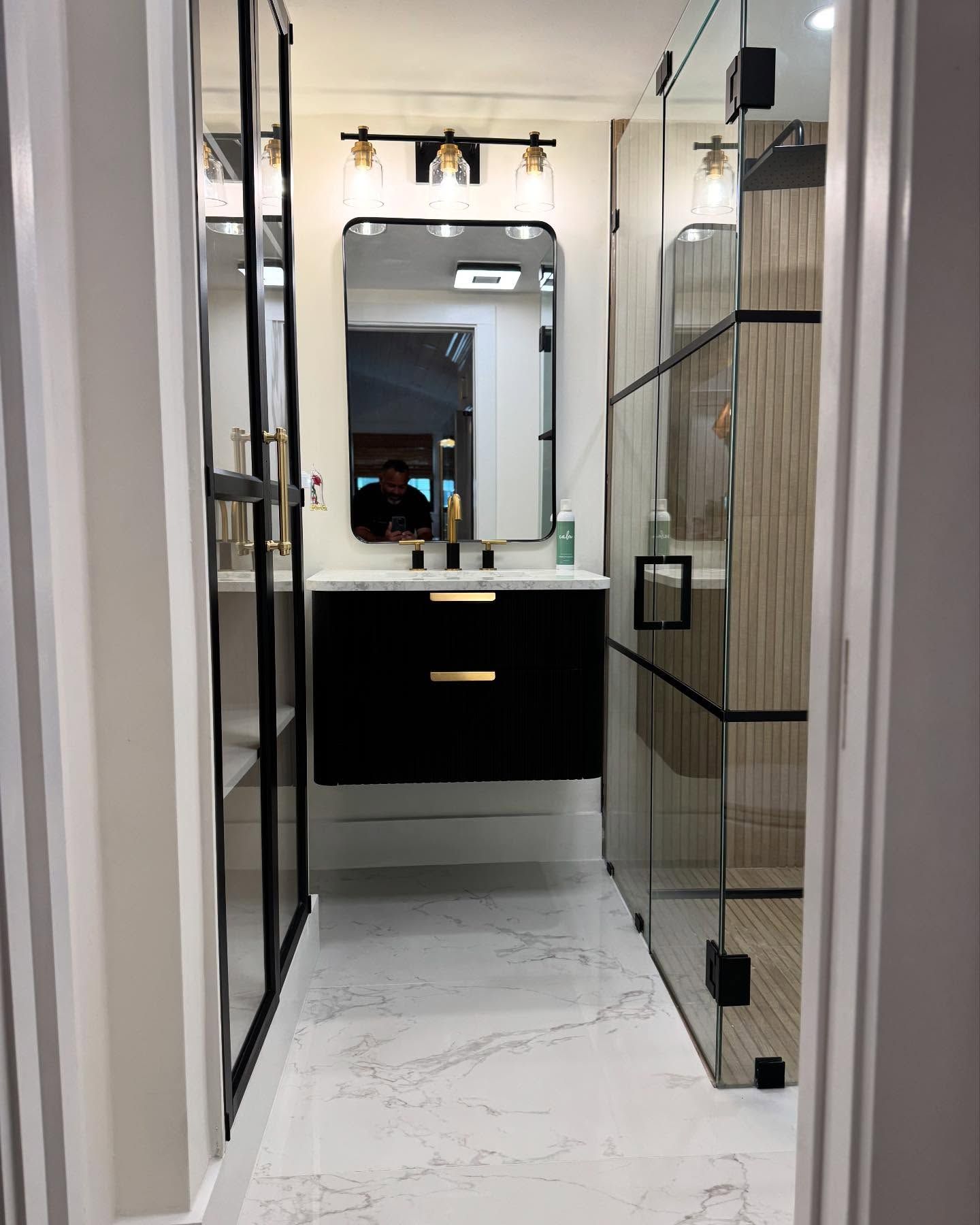 A bathroom with a sink , mirror and walk in shower.