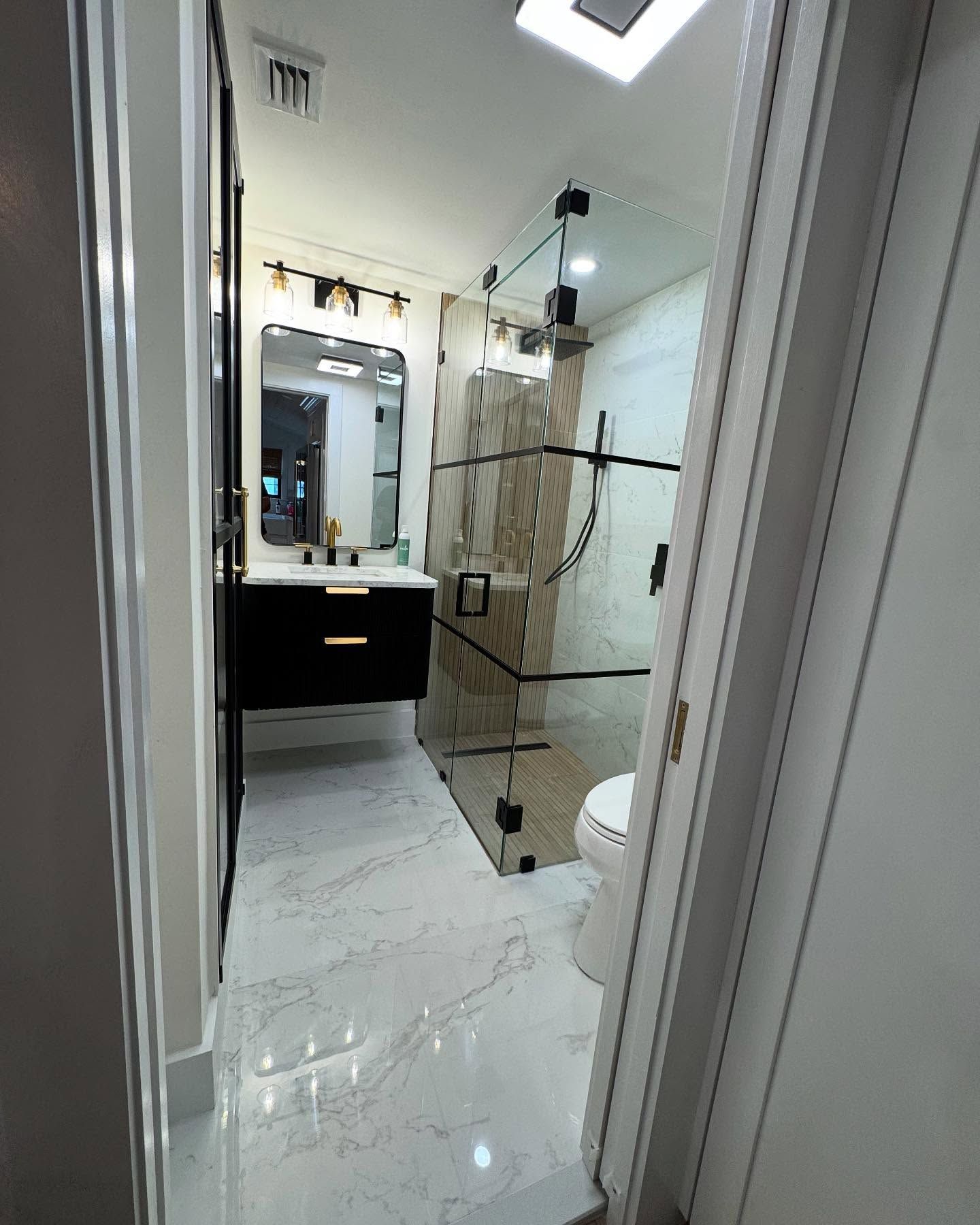 A bathroom with a toilet , sink , mirror and shower.