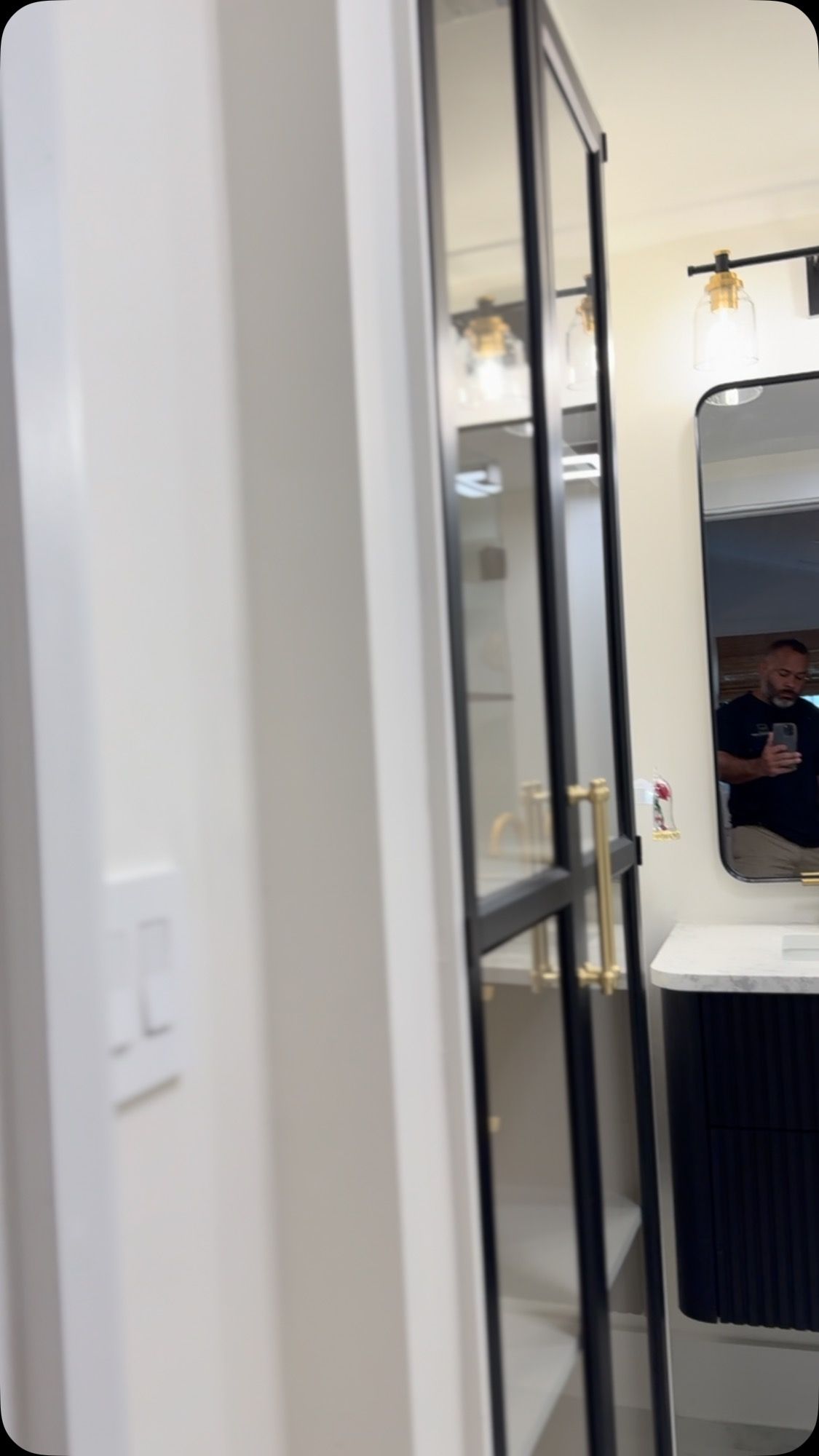 A bathroom with a glass door and a mirror.
