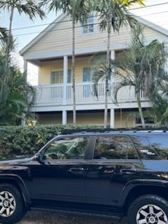 A black suv is parked in front of a house.