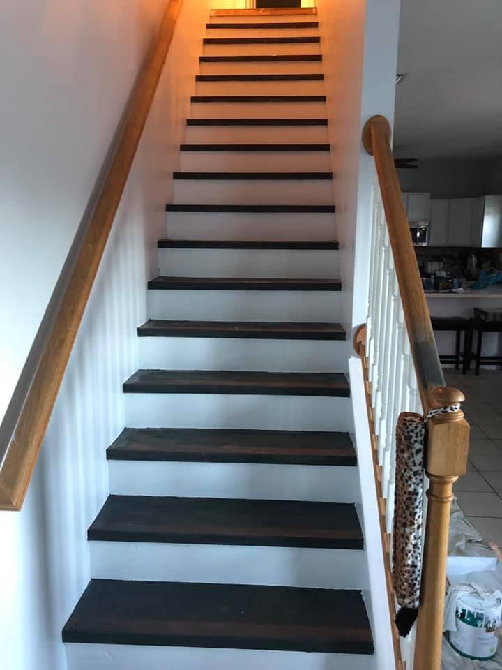 A white staircase with black steps and a wooden railing in a house.