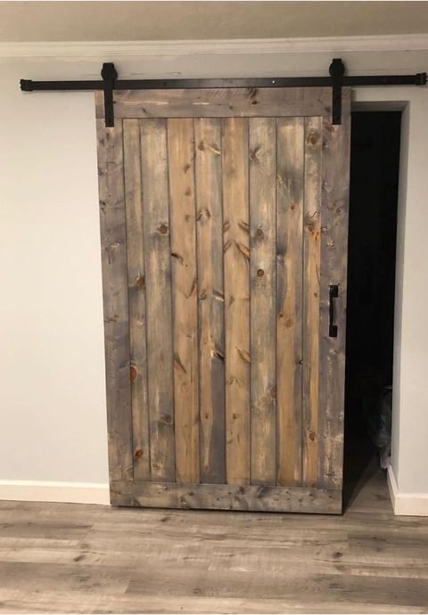 A wooden sliding barn door is hanging on a wall in a room.