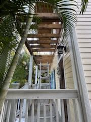 A ladder is sitting on a porch next to a house.