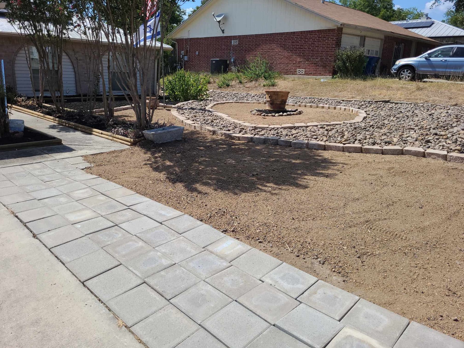 Backyard with paved walkway, gravel landscaping, and a house in the background