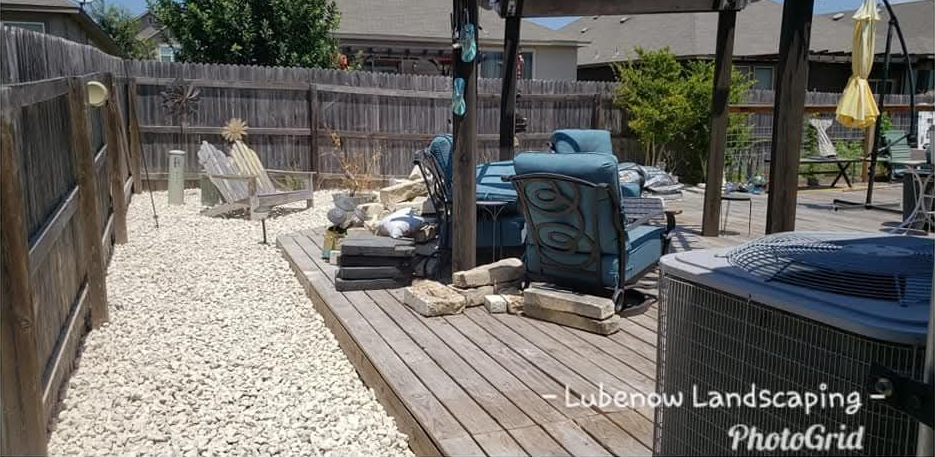 Backyard with dry grass, a brick patio, trees, and a wooden fence on the left