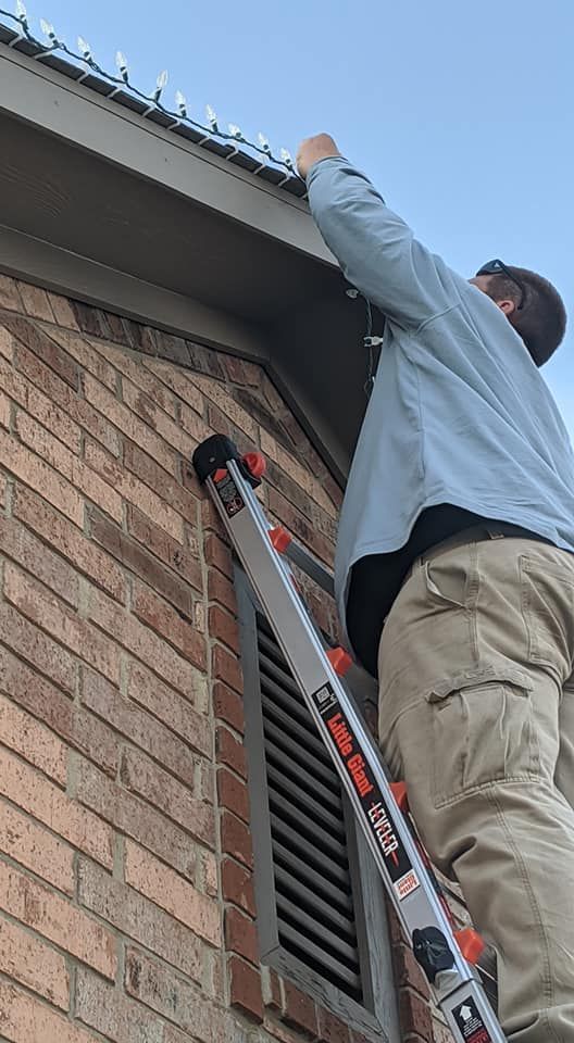 Person on a ladder repairing the roof edge of a brick house