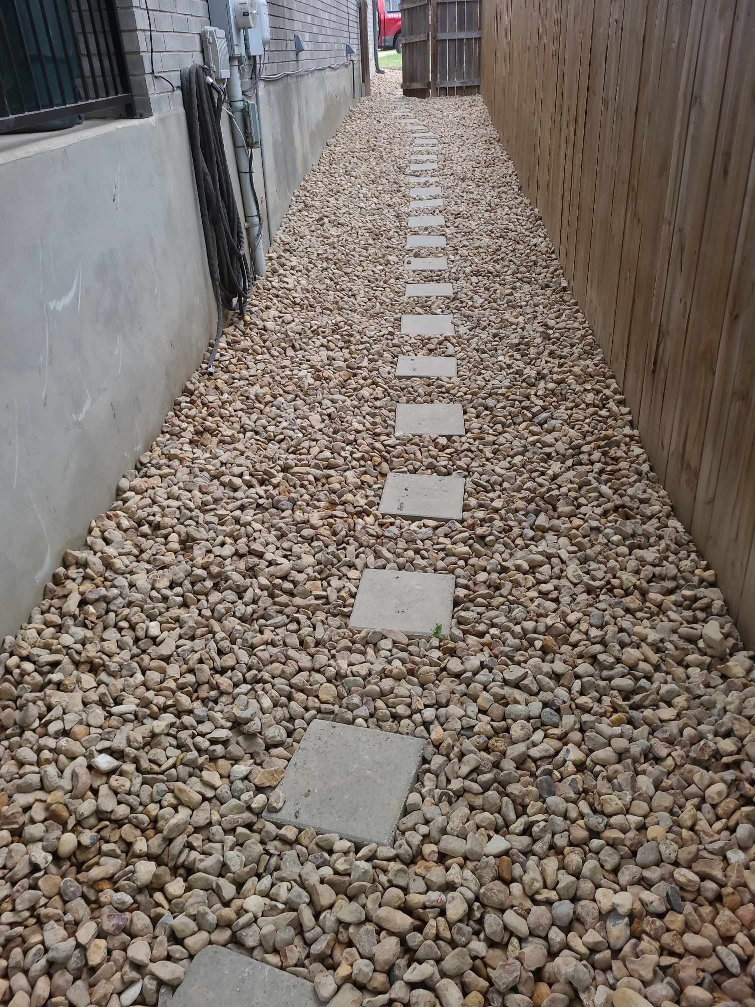 Narrow gravel walkway between walls, with square stepping stones leading into the distance.