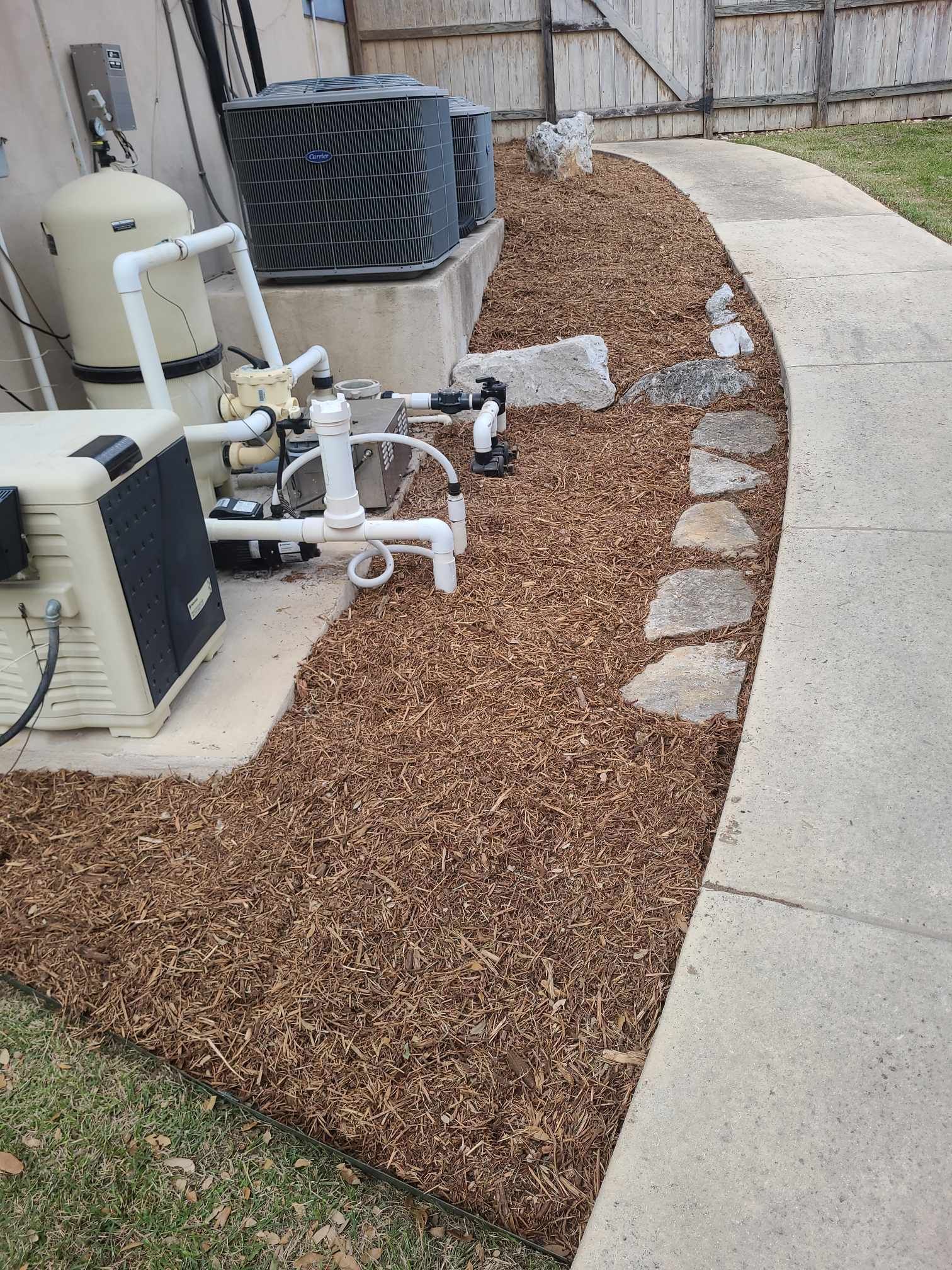 Outdoor HVAC units beside a curved sidewalk with brown gravel and stepping stones