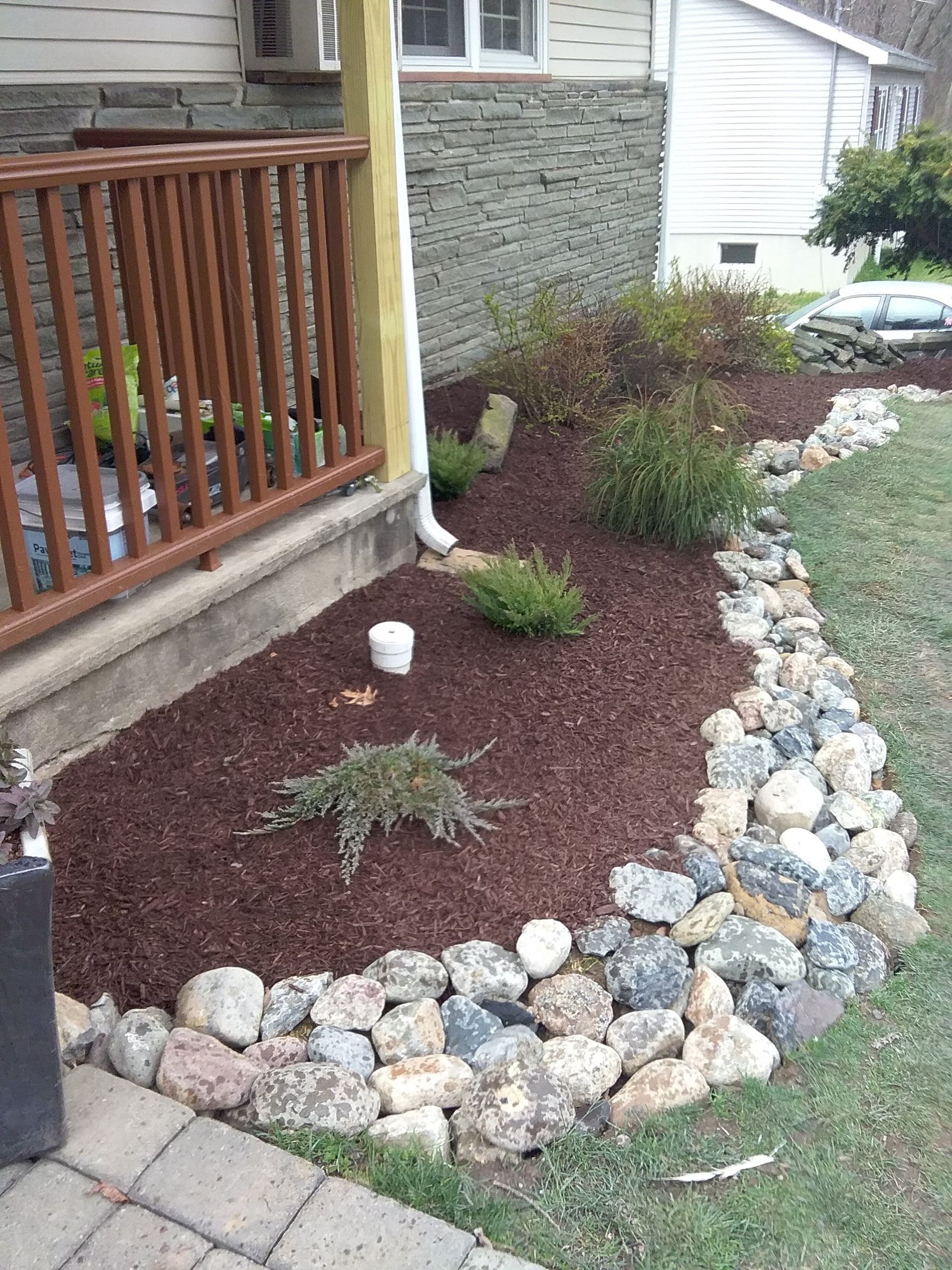 A garden with rocks and mulch in front of a house.
