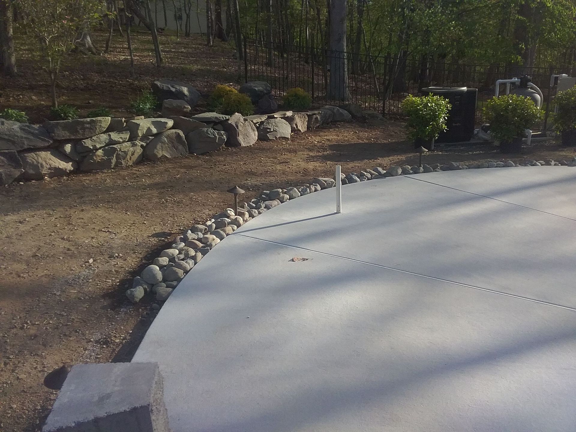 a concrete driveway with rocks and trees in the background