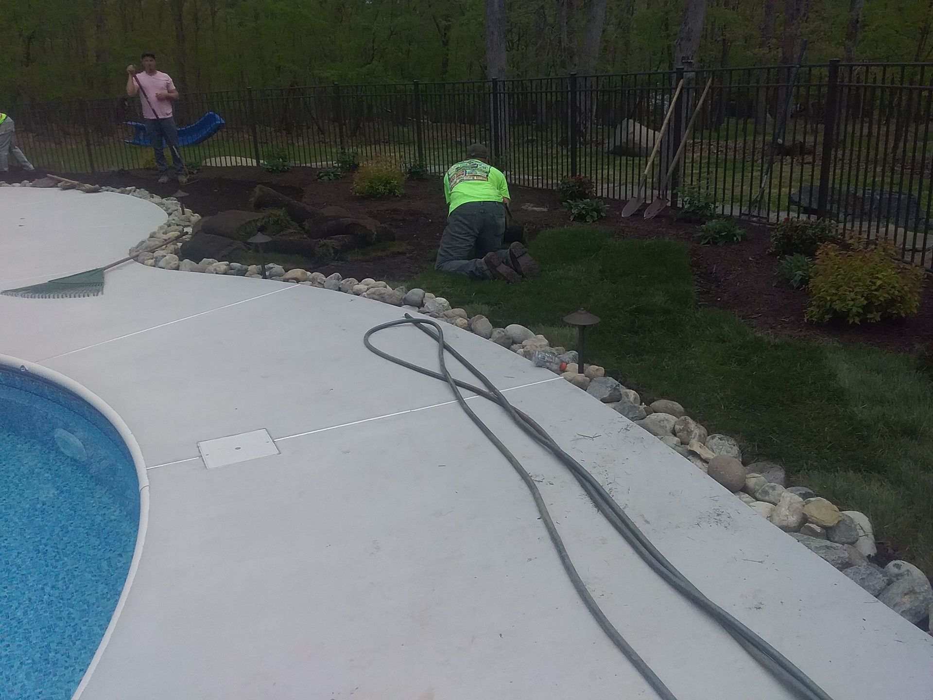a man is kneeling in the grass next to a pool .