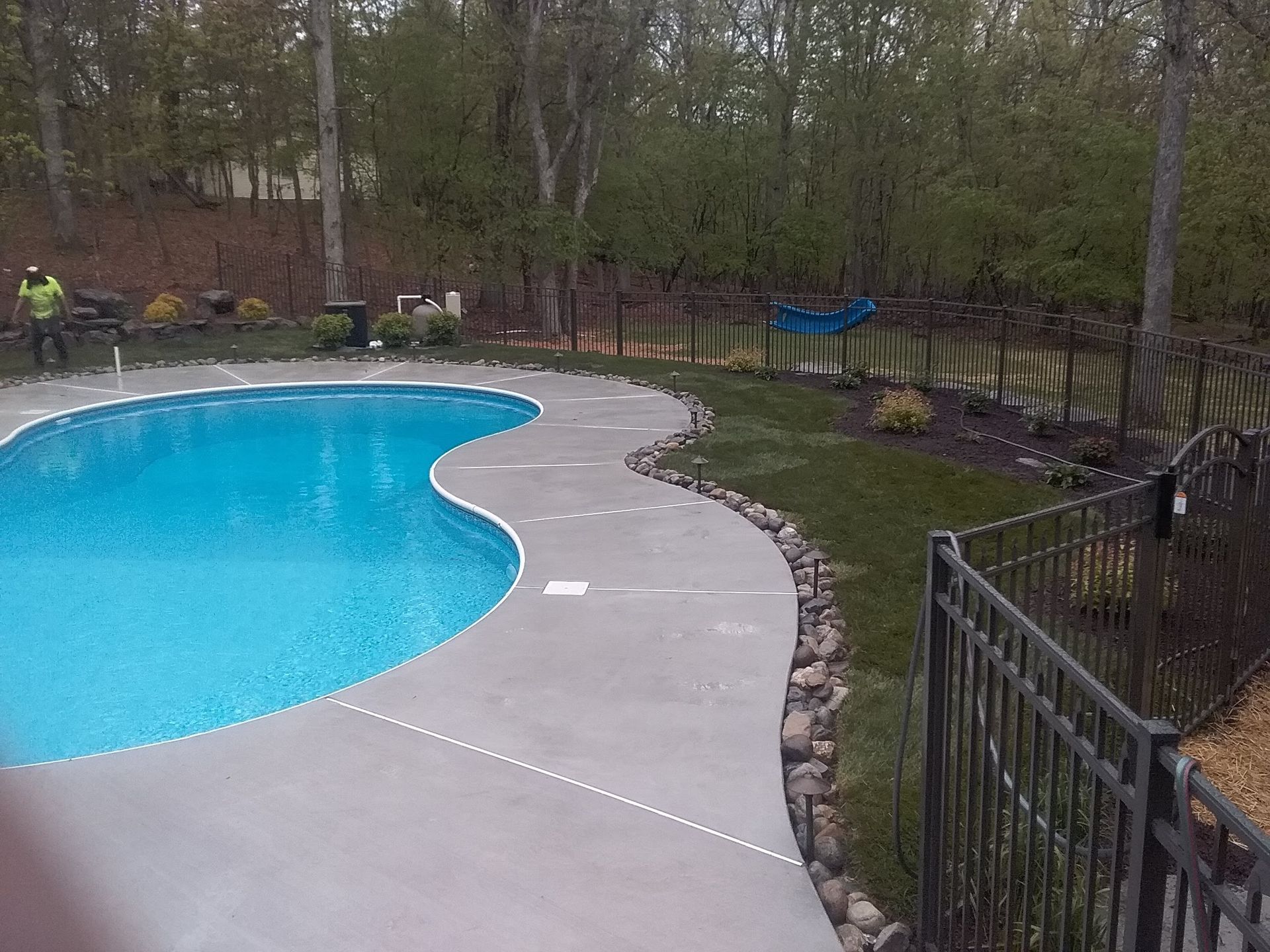 a large swimming pool is surrounded by a fence and trees .