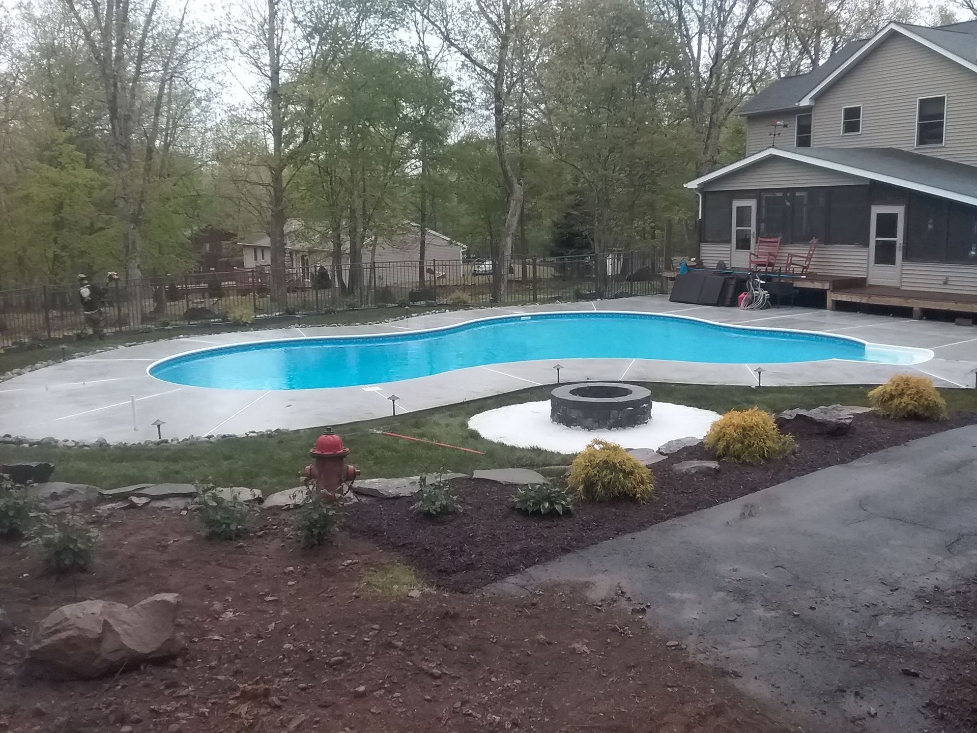 A large swimming pool with a fire pit in front of a house