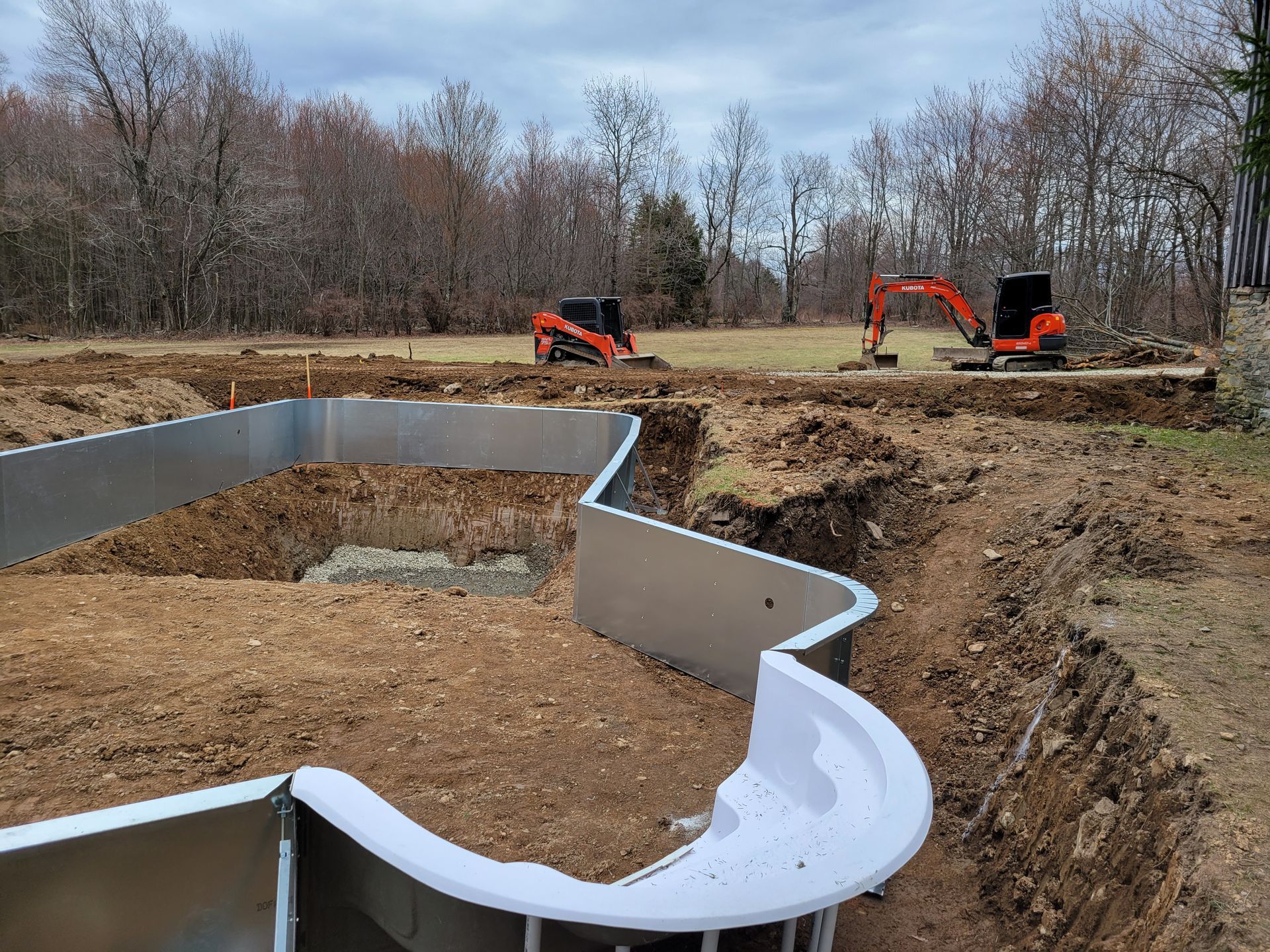 a swimming pool is being built in a field with a bulldozer in the background .