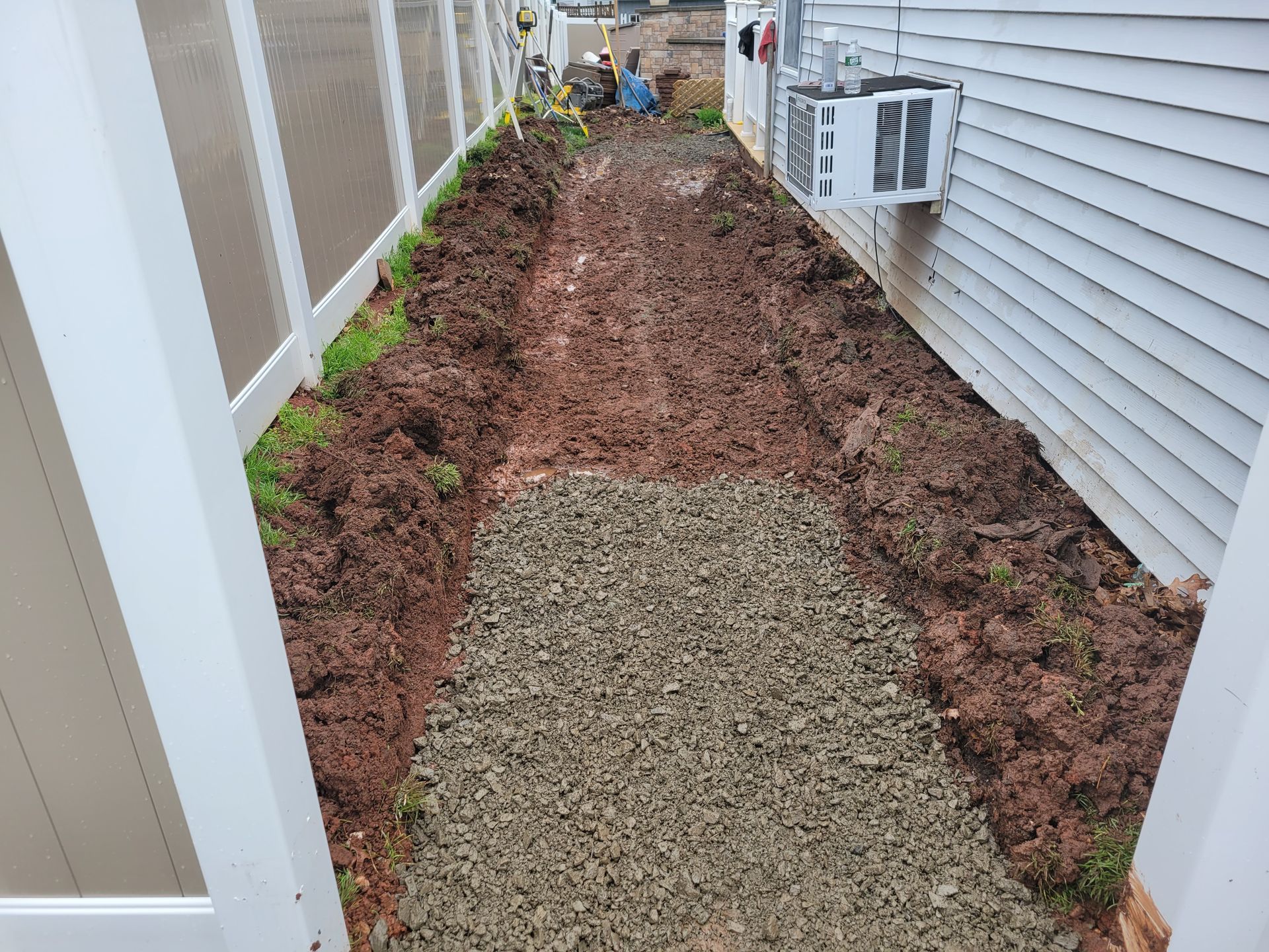 a dirt path leading to a house with a white fence .