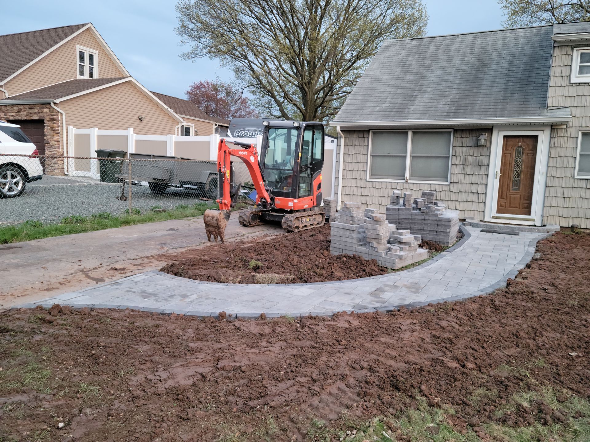 A small orange excavator is sitting in front of a house.
