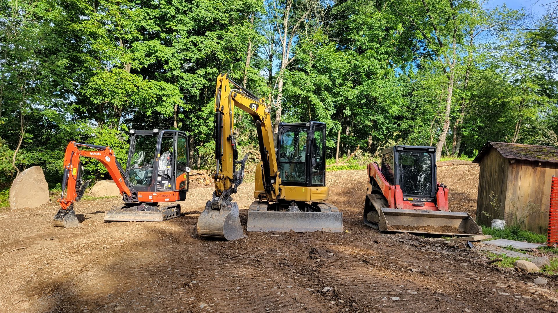 a group of A.A.F Landscaping construction vehicles are parked in a dirt field .