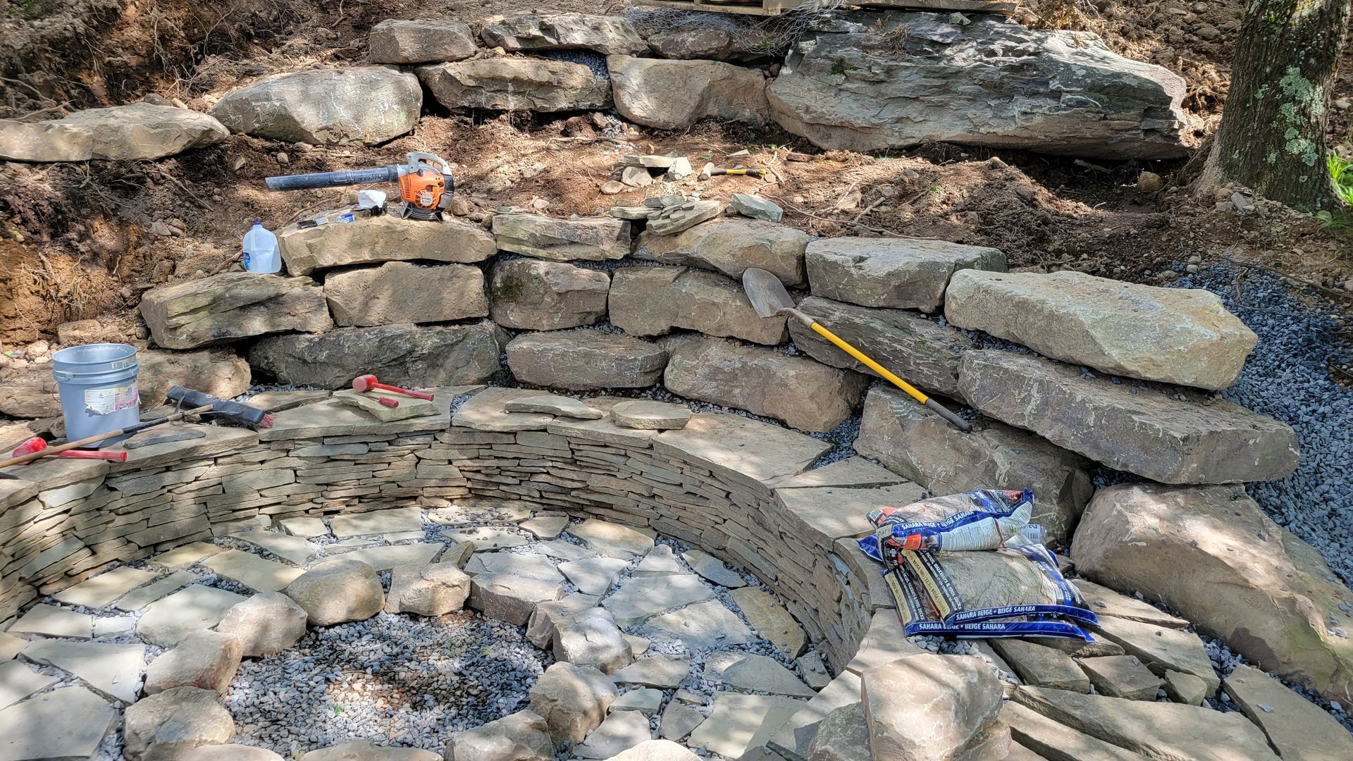 A stone wall is being built around a fire pit.