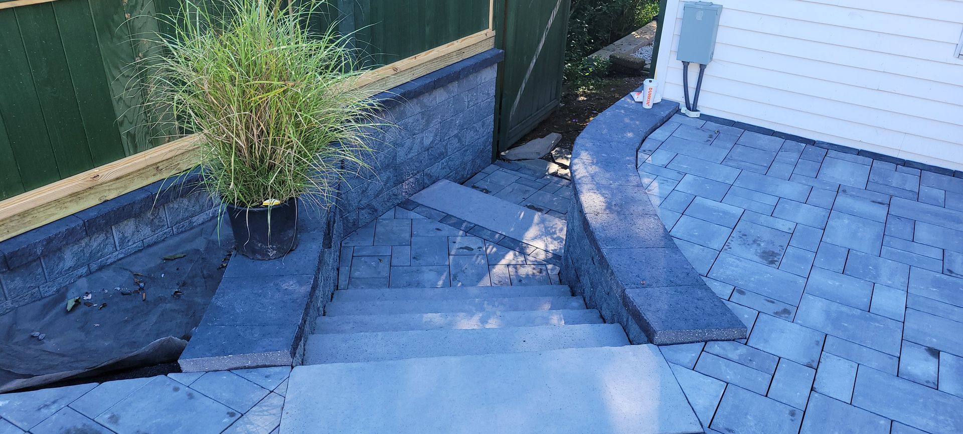 A staircase leading up to a patio with a potted plant on the side of it.
